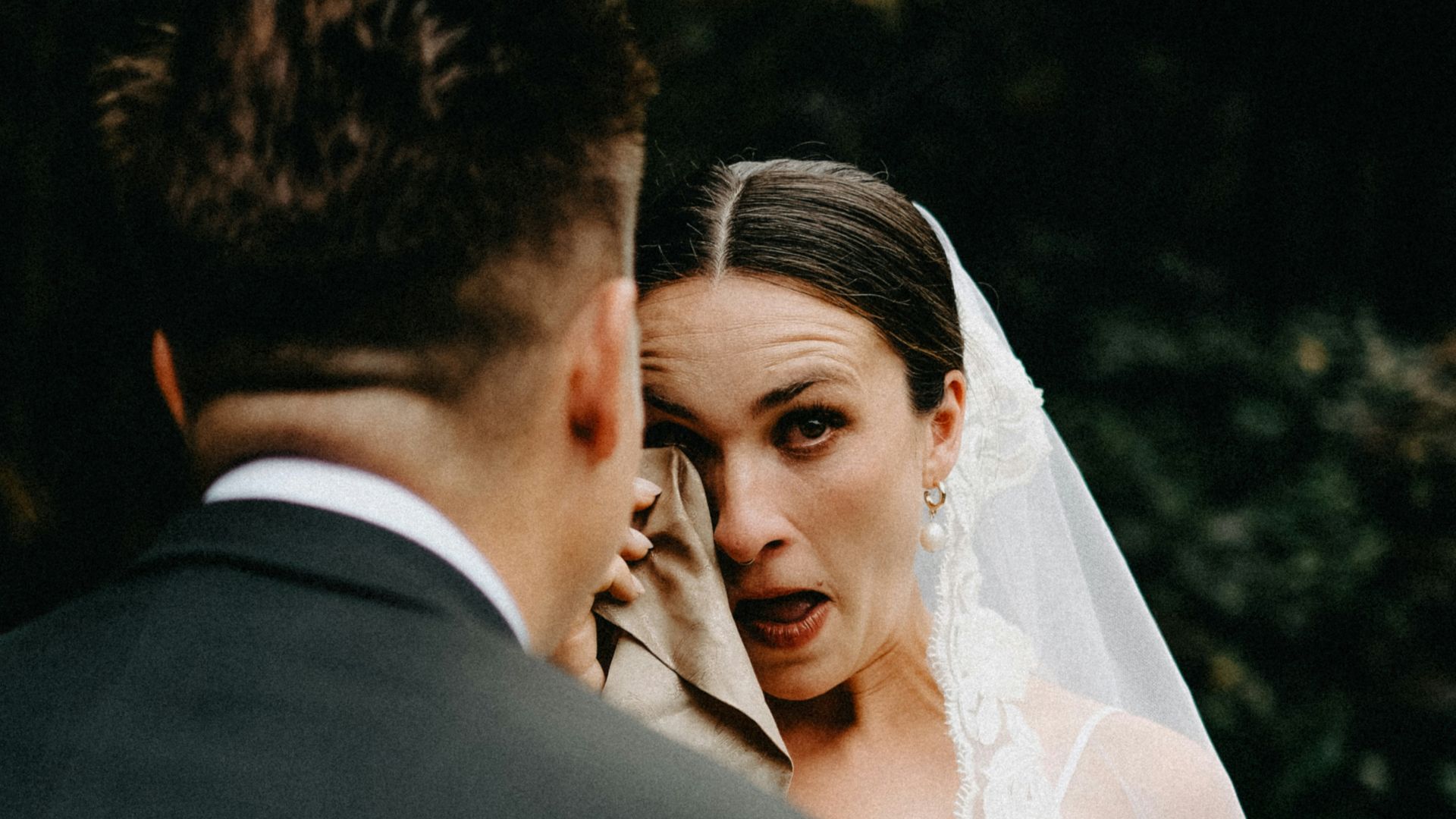 Bride cries while wiping eyes with cloth.