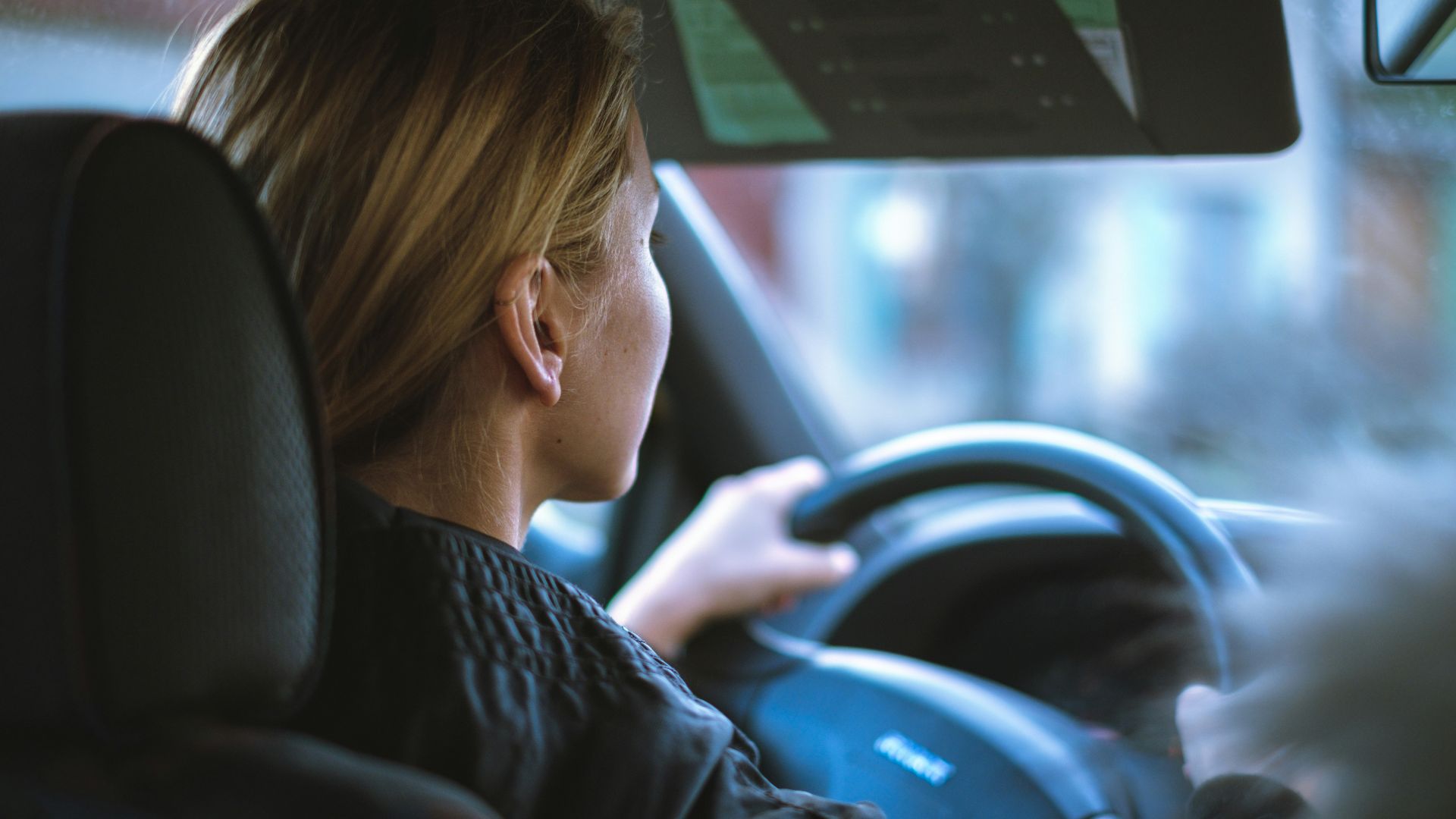 a woman sitting in a car with a steering wheel