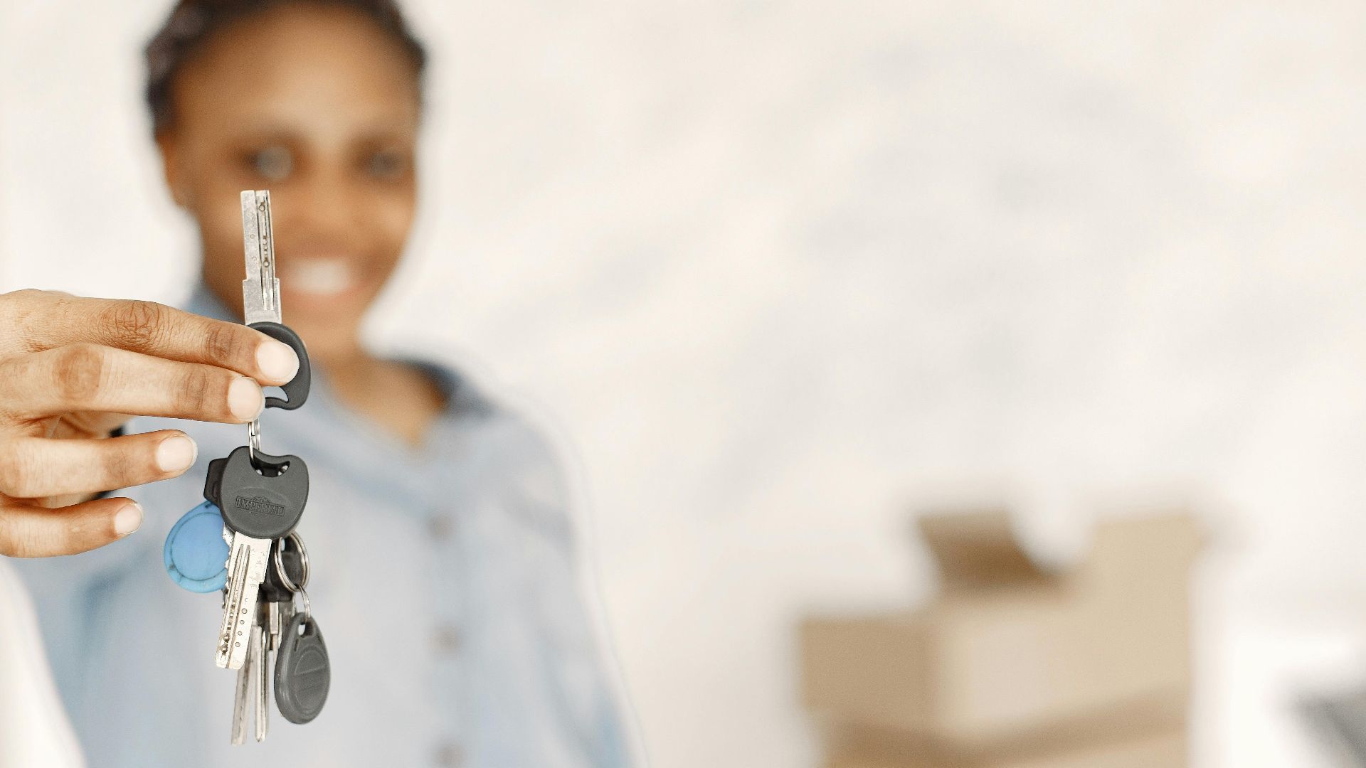 Close-up of a woman holding keys with a blurred background, symbolizing a new home or real estate concept.