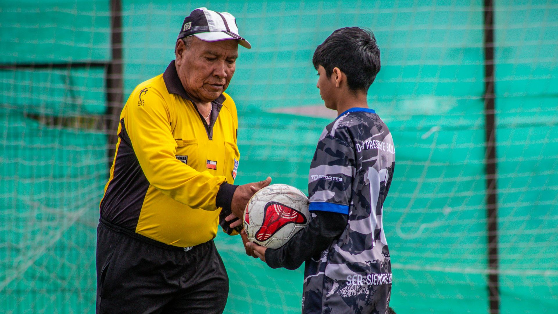 An adult coach and young players during a soccer practice session outdoors in Chile.