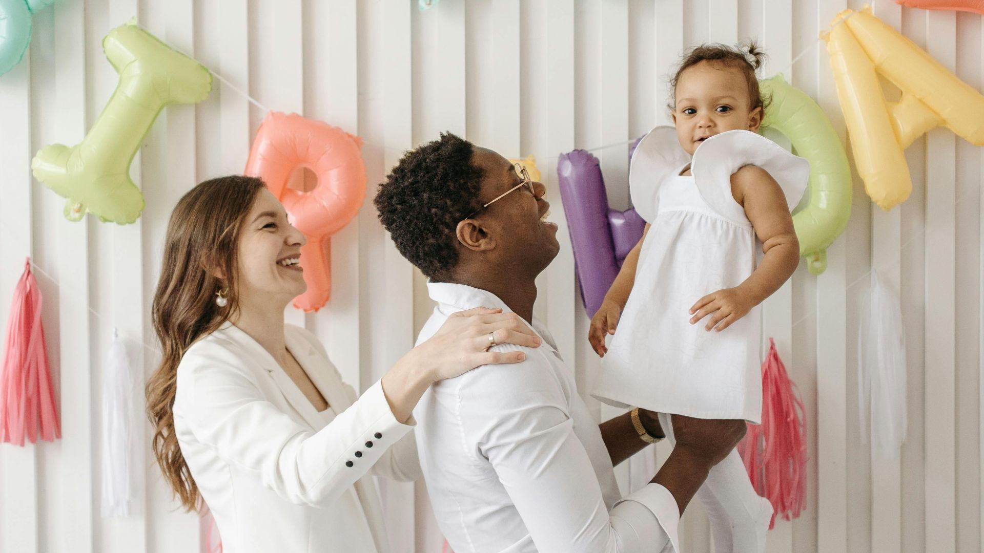 A happy family celebrating their daughter's birthday with colorful balloons.