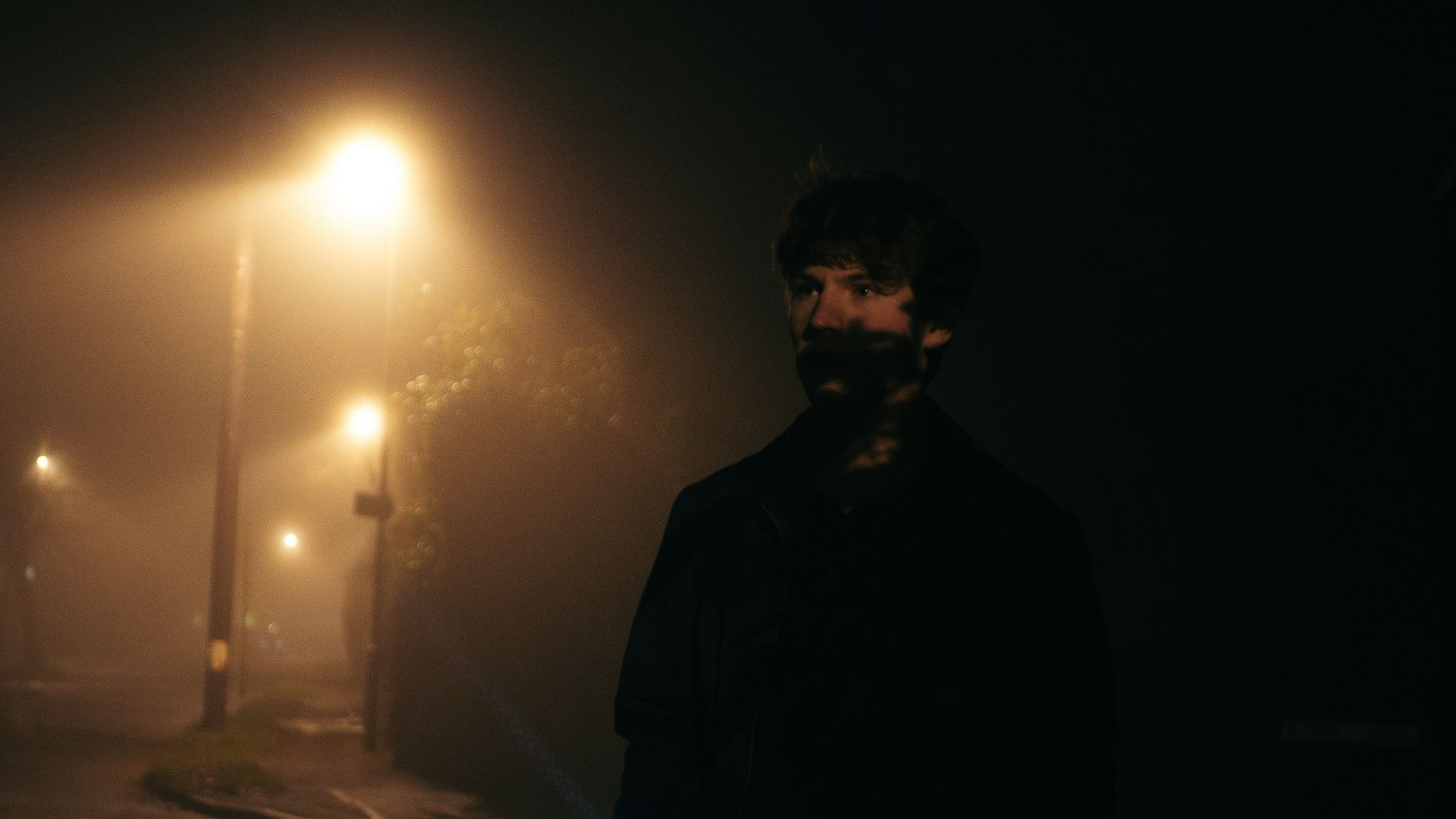 A man standing on a street at night