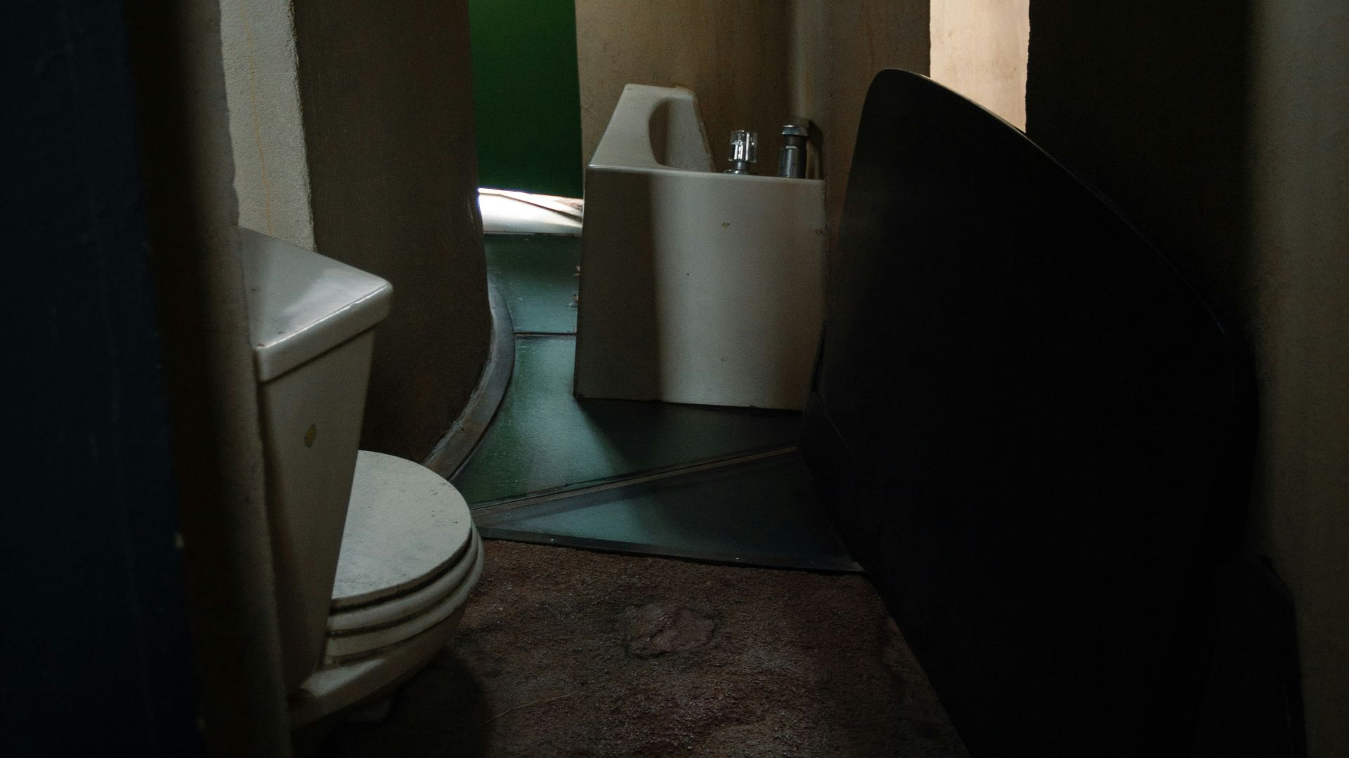 A dimly lit bathroom with a toilet and sink.