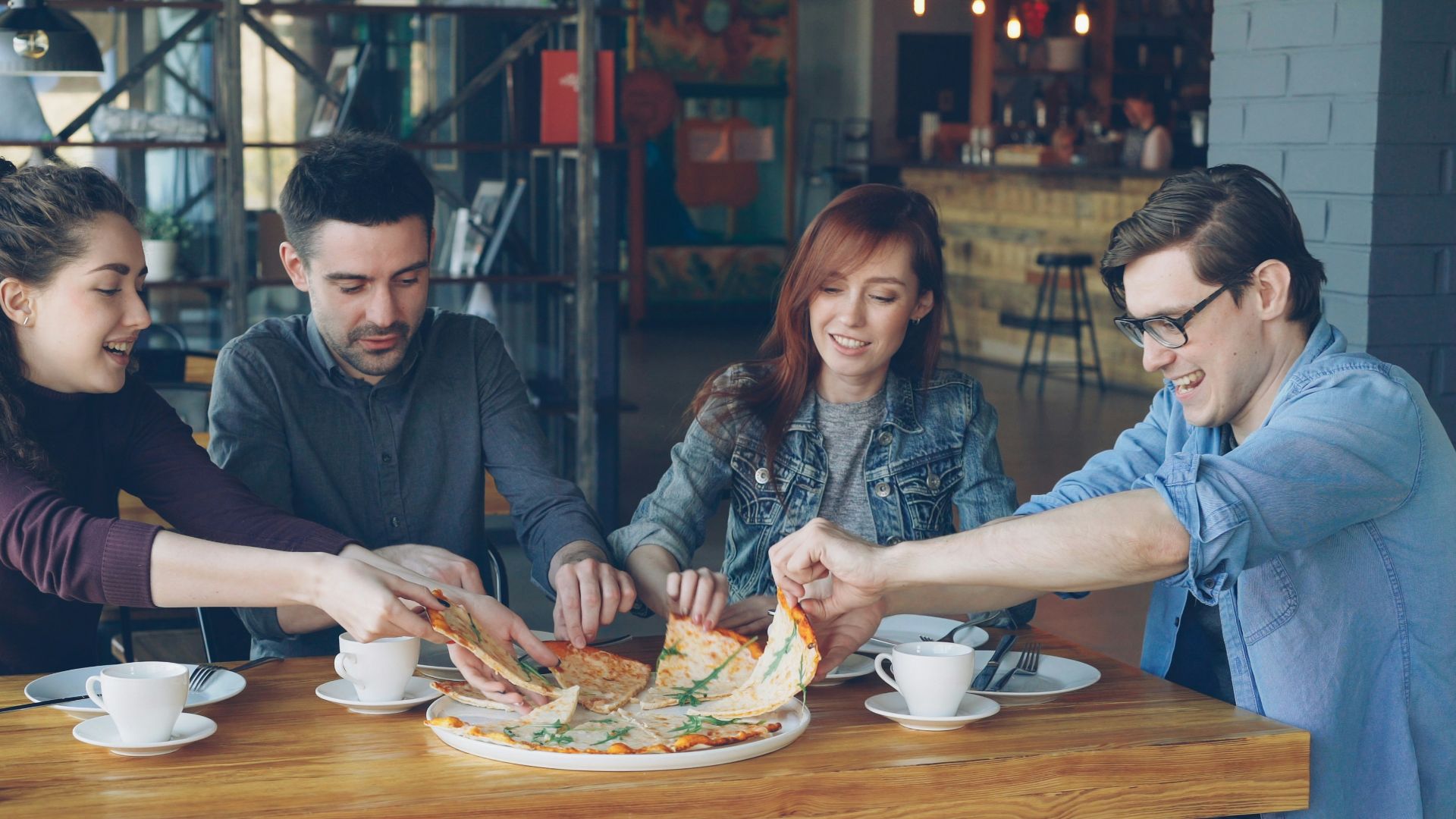 Friends are sharing a pizza at a restaurant.