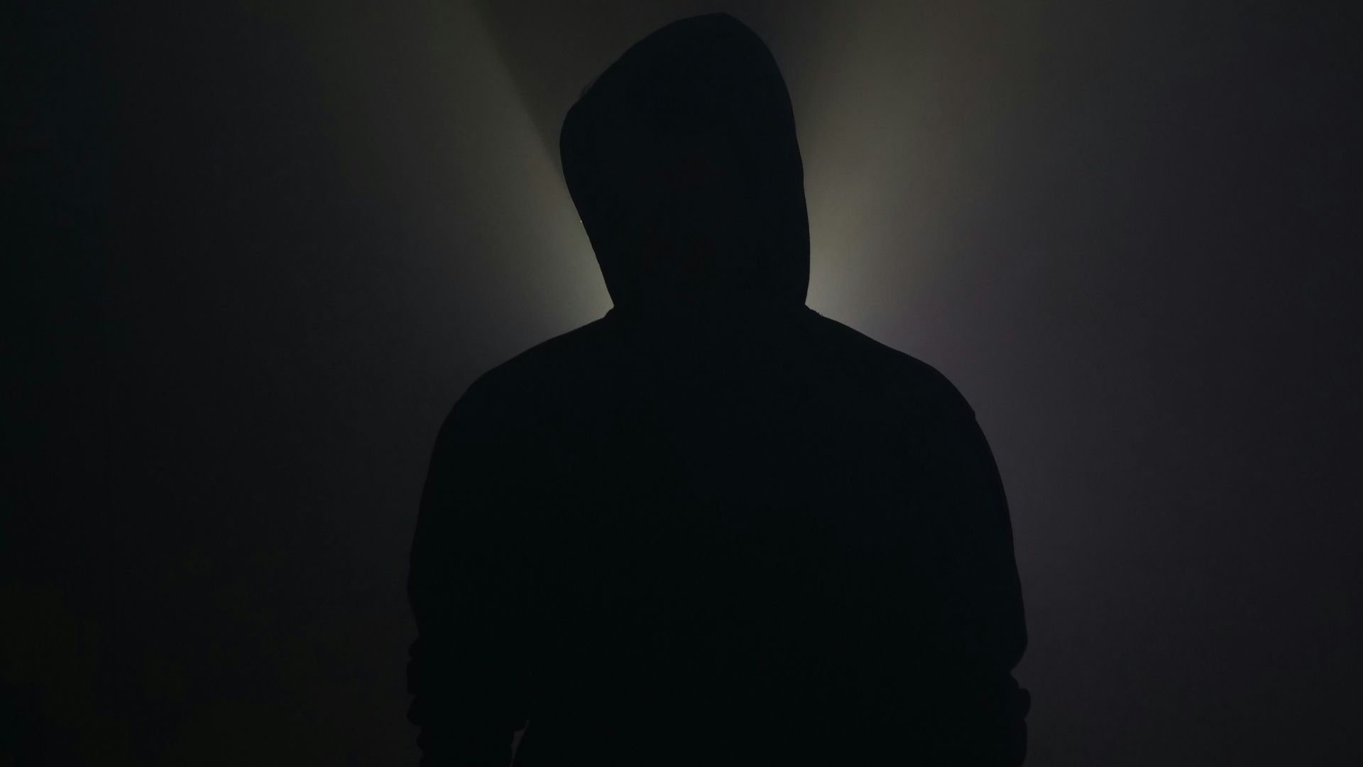 A silhouette stands illuminated in the darkness.