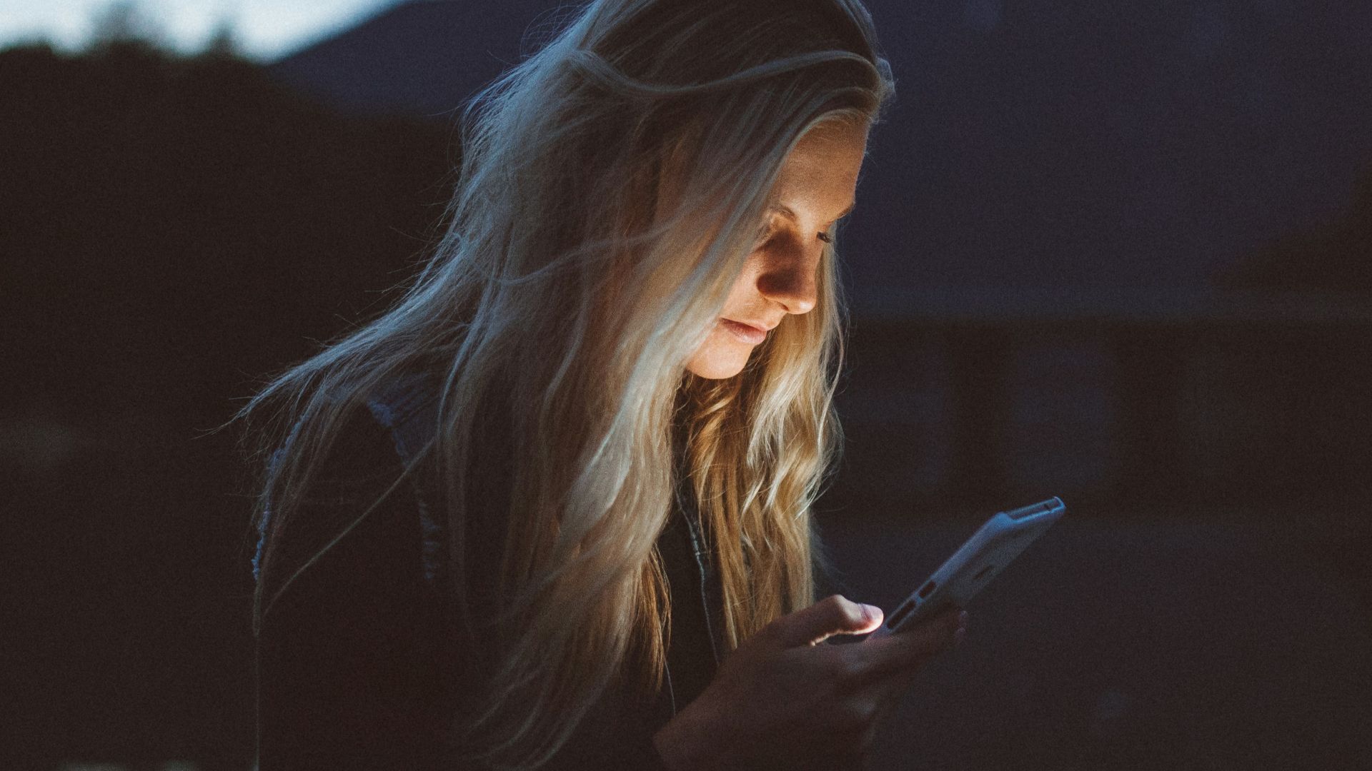 woman looking at phone beside body of water