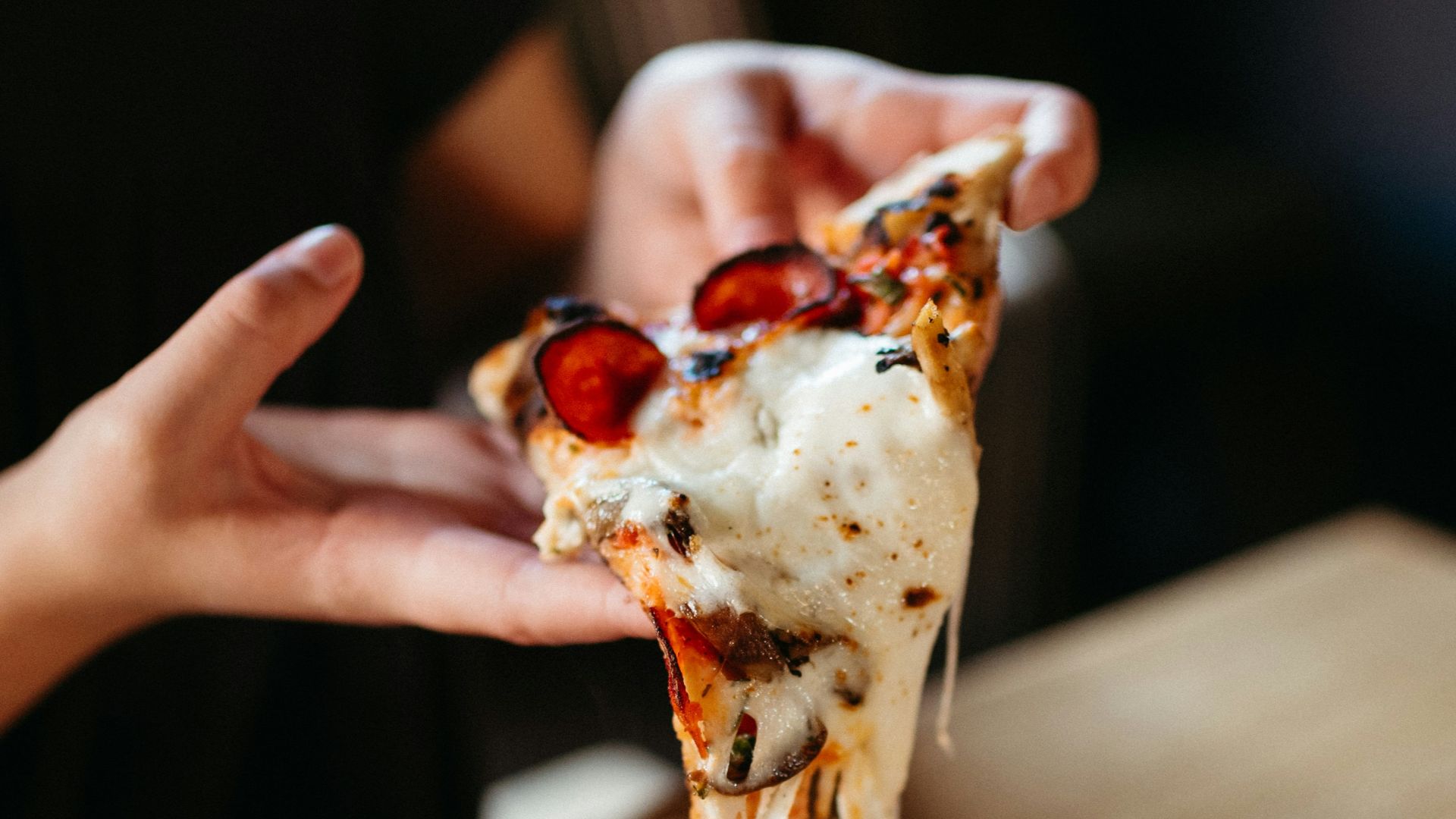 a person takes a slice of pizza