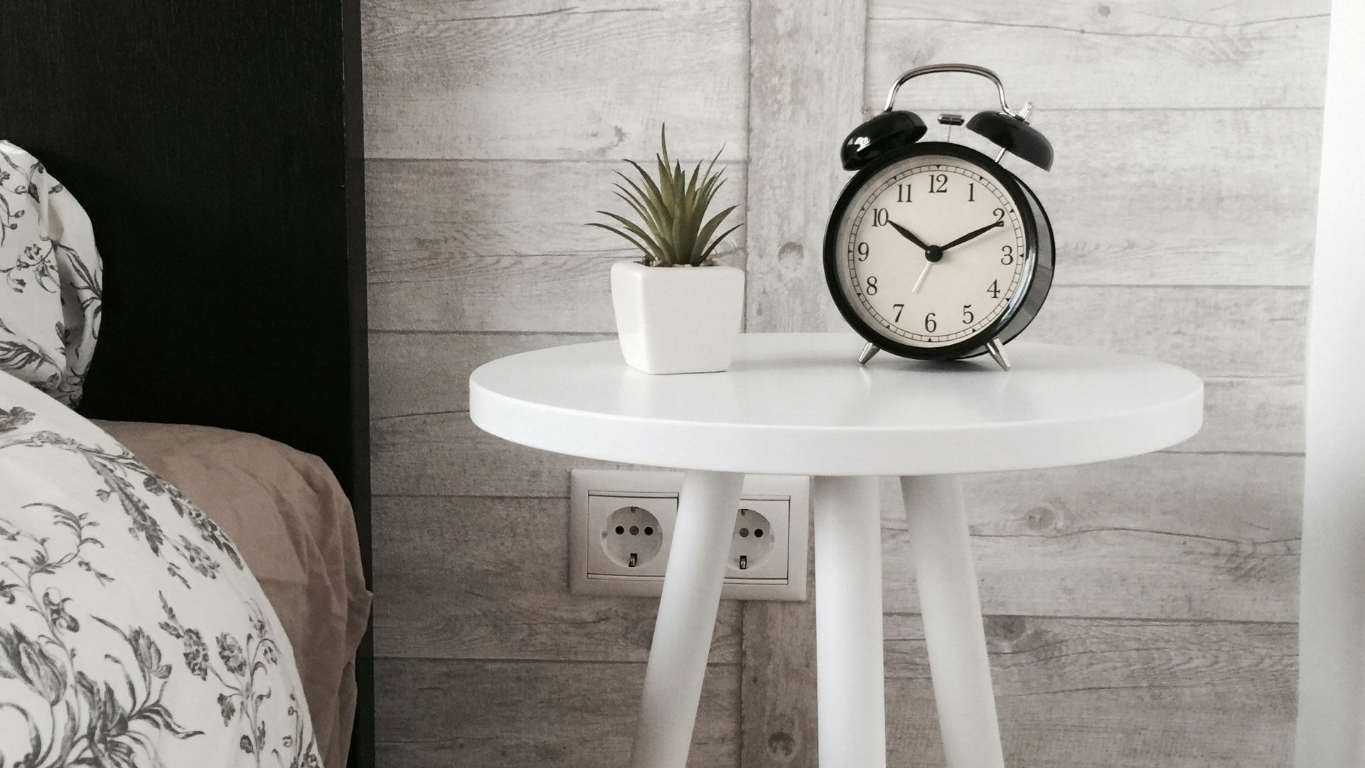 black alarm clock at 10:10 on white wooden table near table