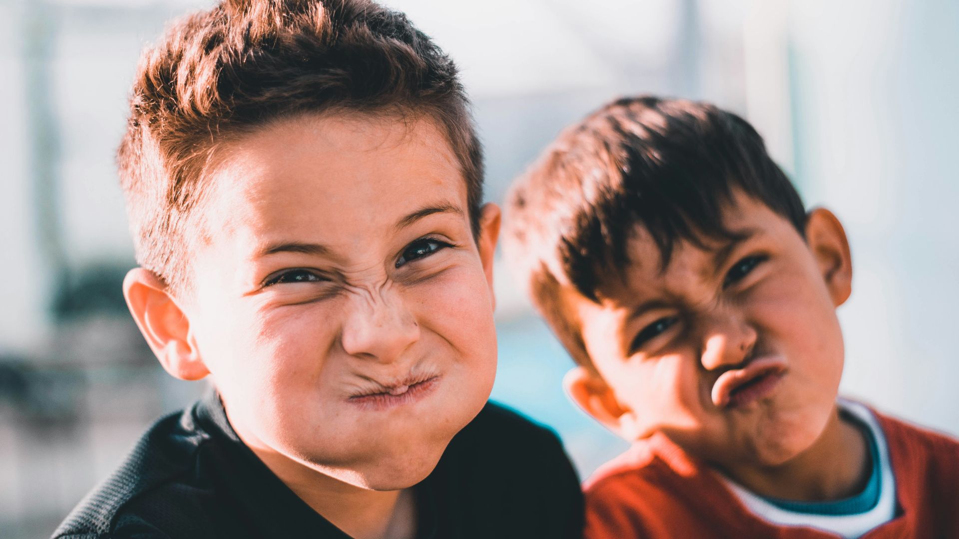 shallow focus photography of two boys doing wacky faces