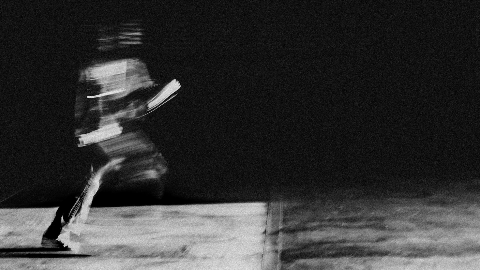 grayscale photo of woman in white shirt and black pants sitting on concrete floor
