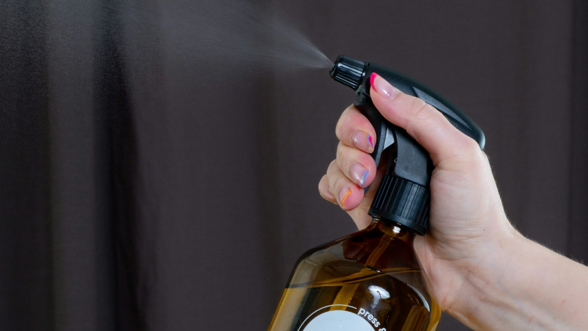 a person spraying a brown bottle with a sprayer