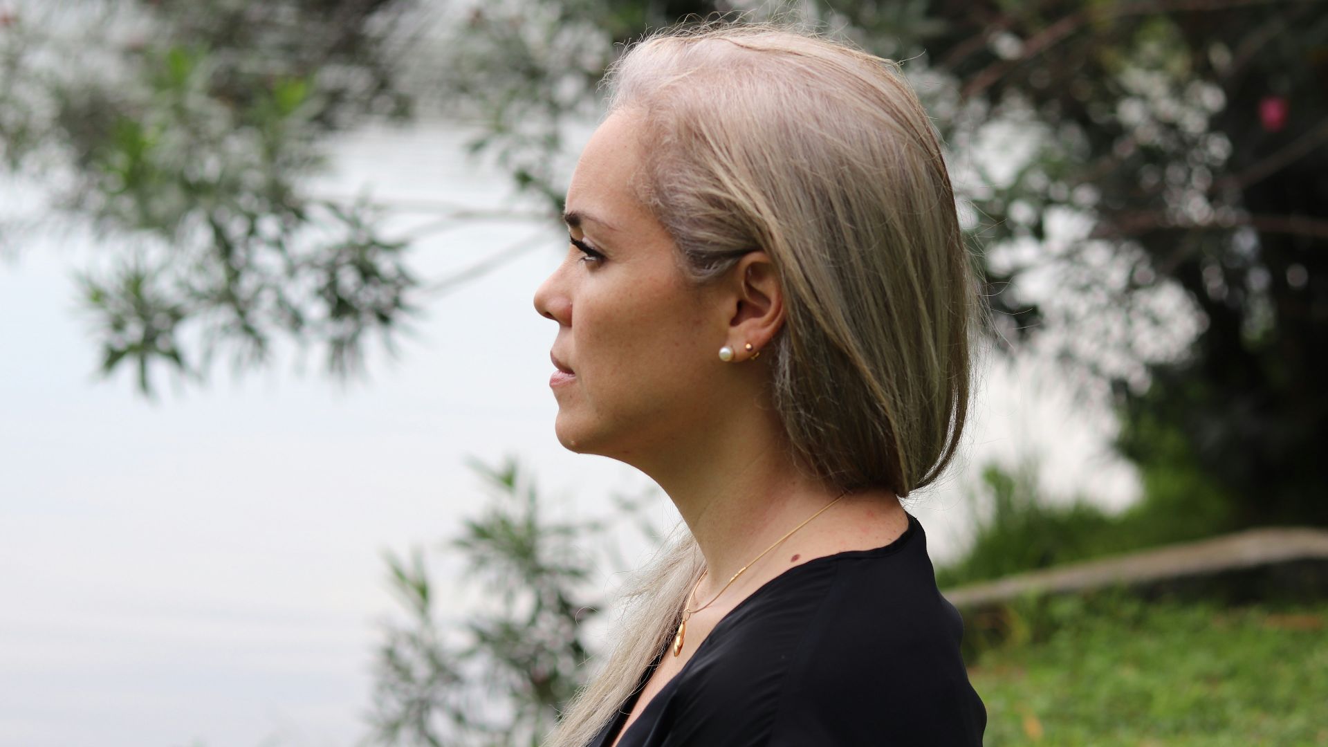 a woman with blonde hair standing in front of a body of water