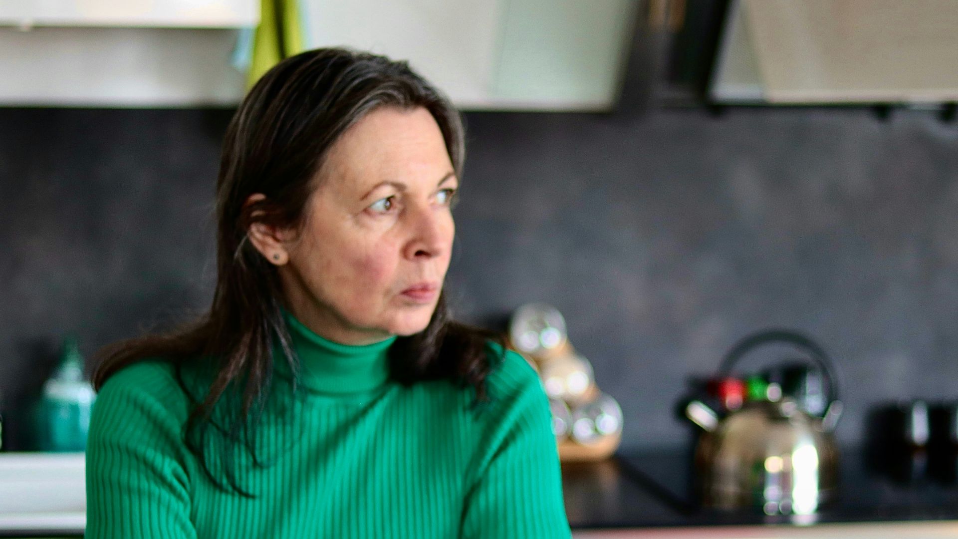 a woman sitting at a table in a kitchen