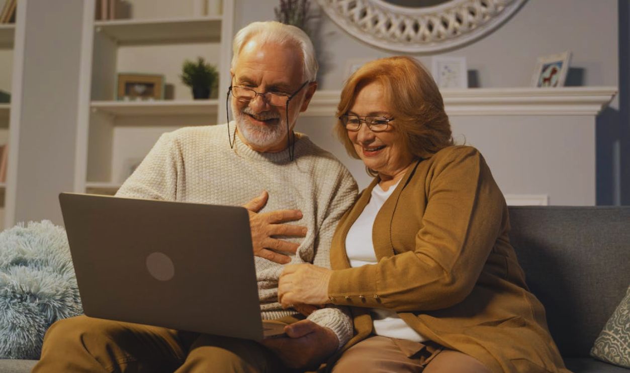 Elderly Couple Sitting on a Couch while in a Video Call Using a Laptop