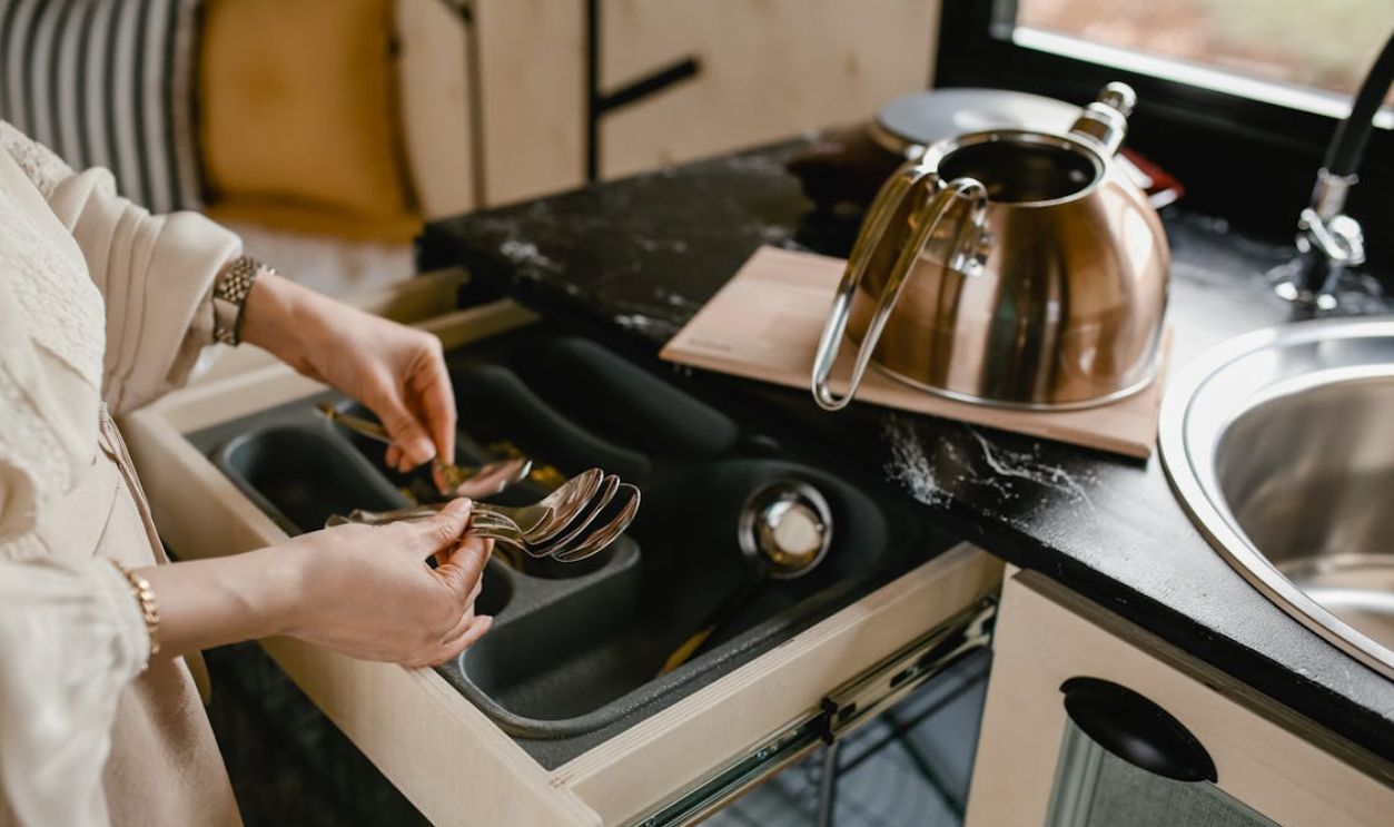 Unrecognizable Woman Putting Table Spoons in Drawer