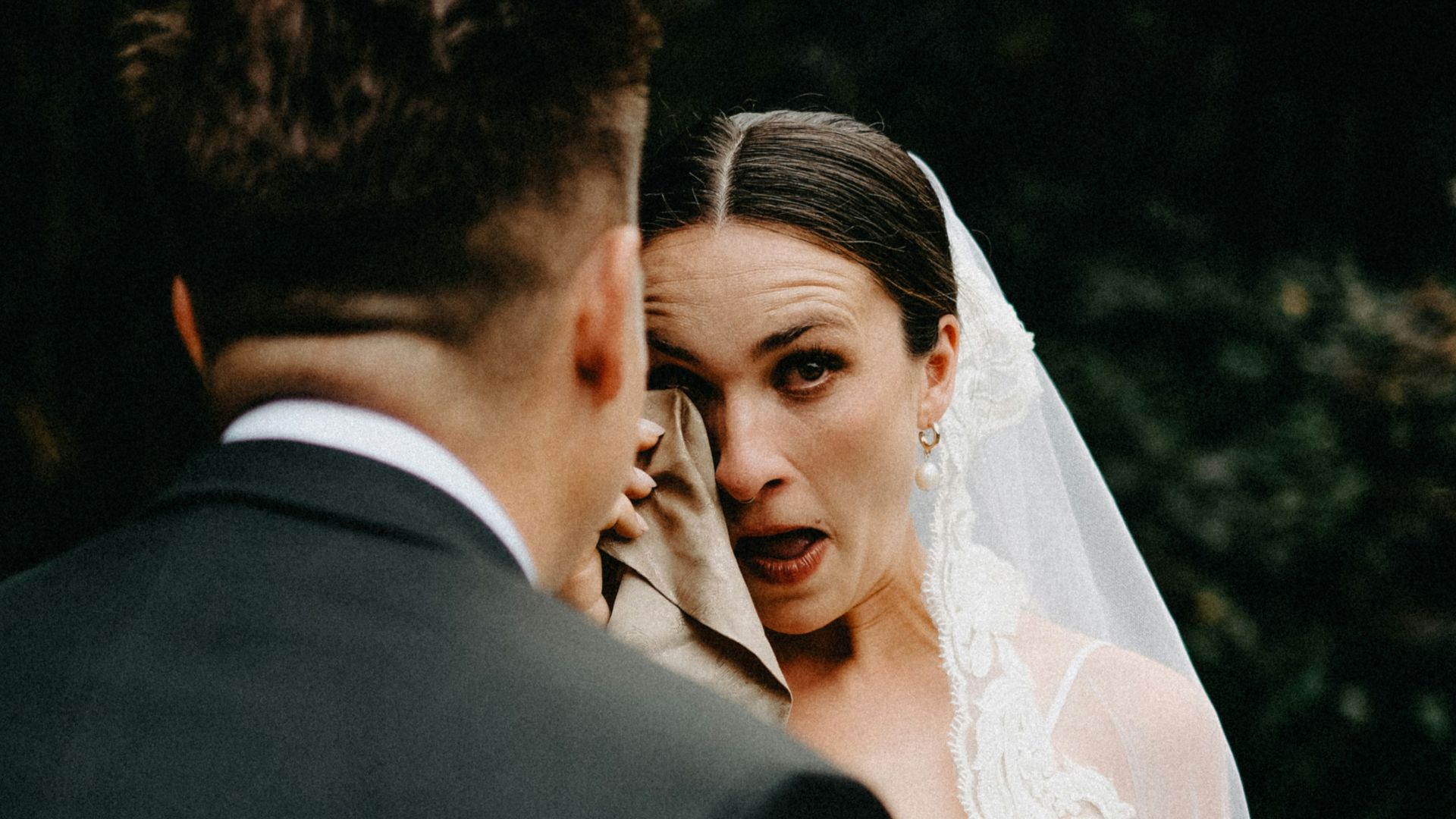 Bride cries while wiping eyes with cloth.