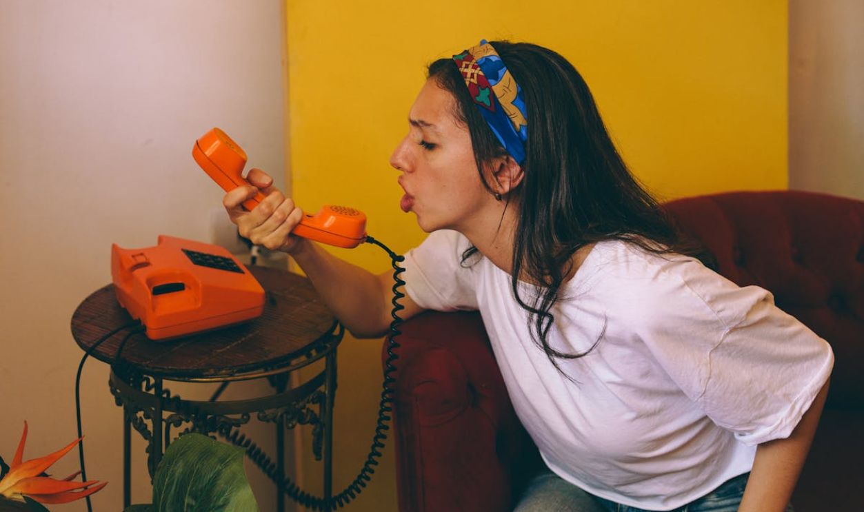 Young Woman Using Vintage Orange Rotary Phone