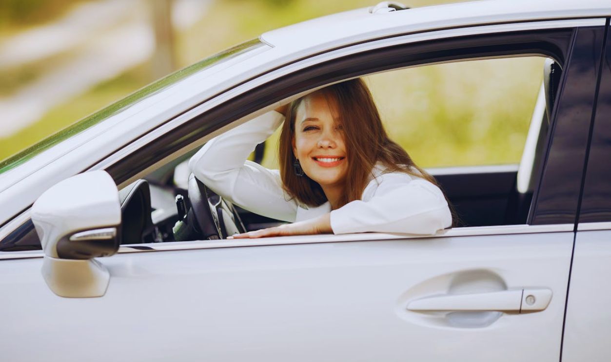 Happy elegant woman sitting in car smiling at camera