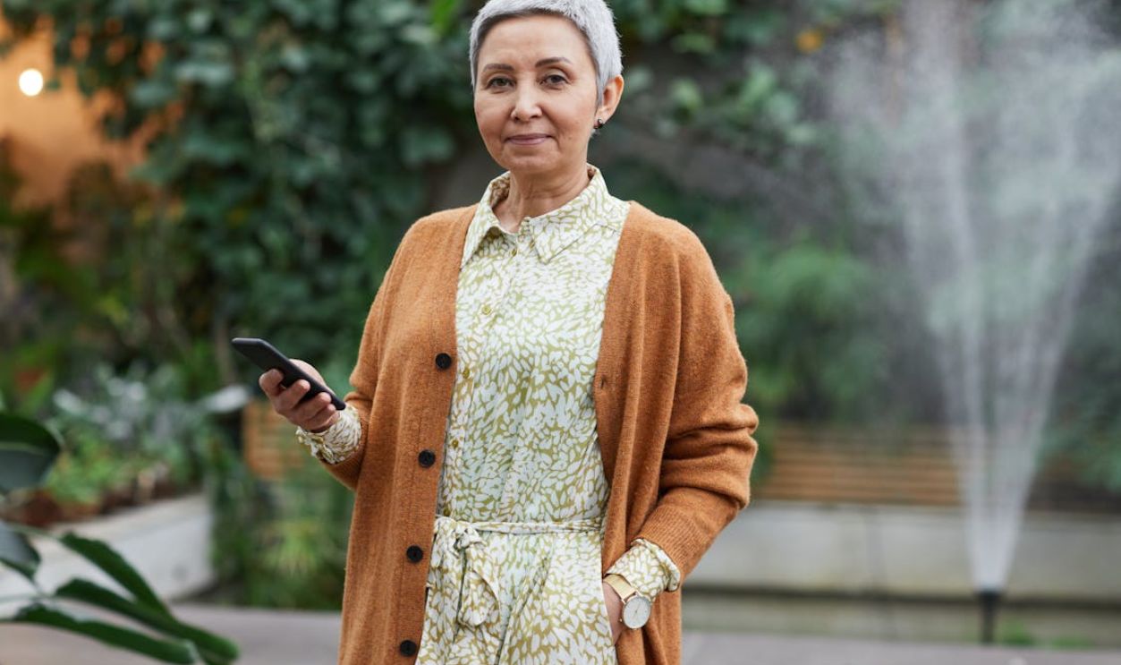 Woman Holding Her Smartphone While Smiling at the Camera