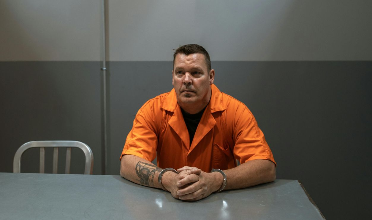 Man in Orange Shirt Sitting on Chair