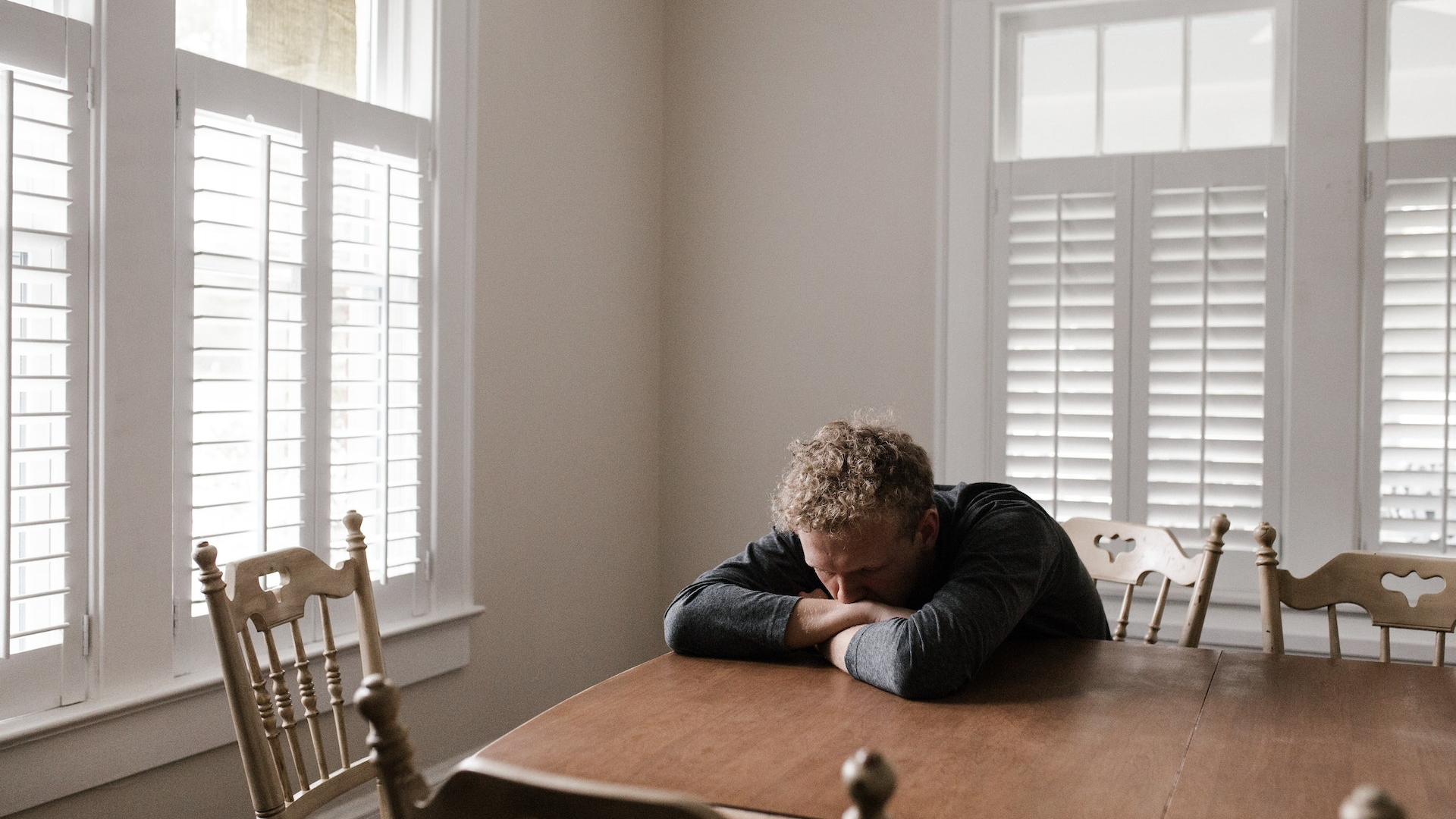 Man in Gray Long Sleeve Shirt Sitting on Brown Wooden Chair