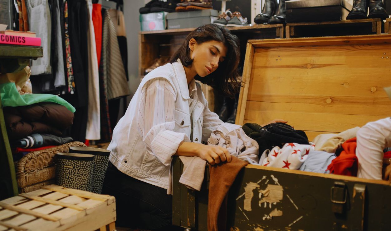 Woman in White Long Sleeve Shirt Sitting on the Floor beside Brown Wooden Box