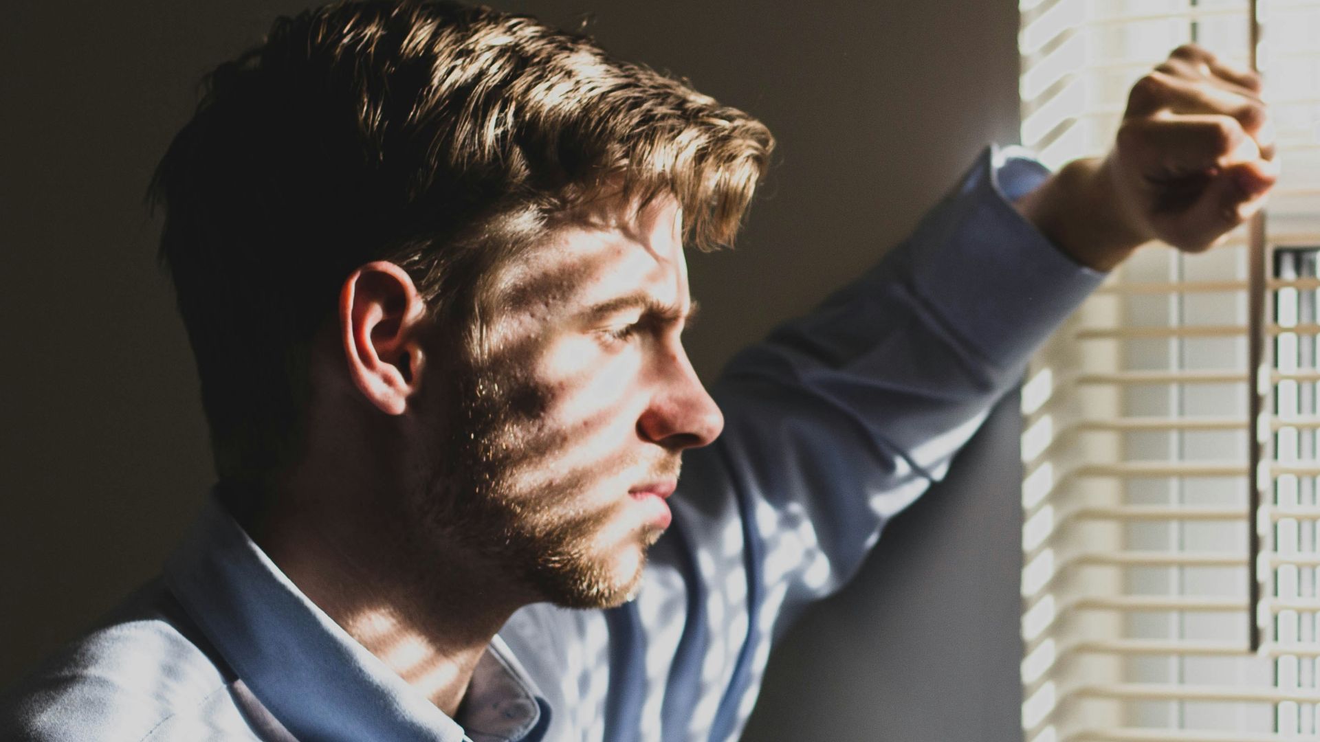 person near clear glass window pane and window blinds low-light photography