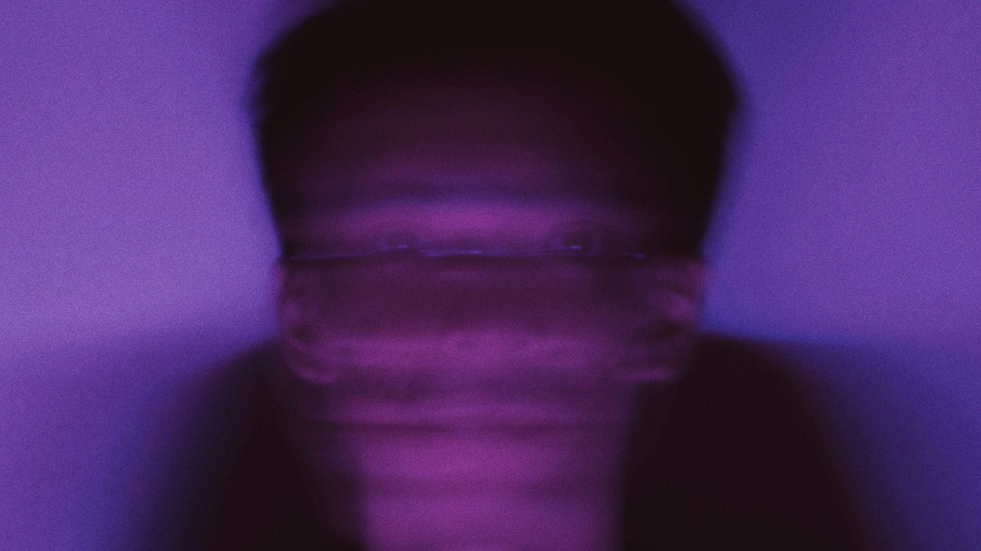 a man standing in front of a purple wall