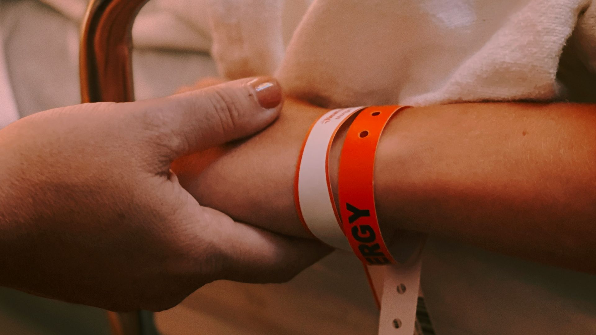 person wearing orange and white silicone band