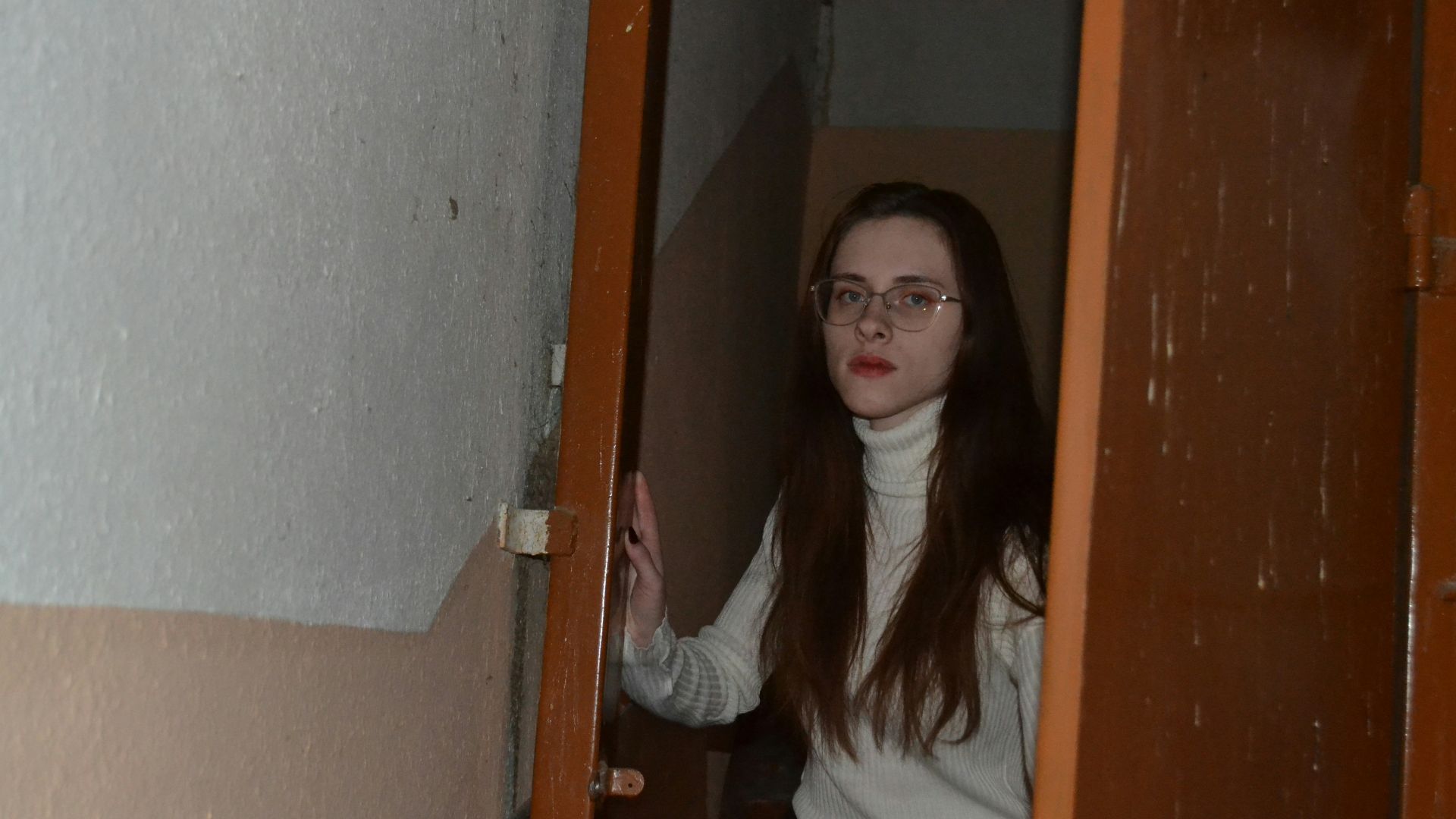 a woman with glasses standing in a doorway