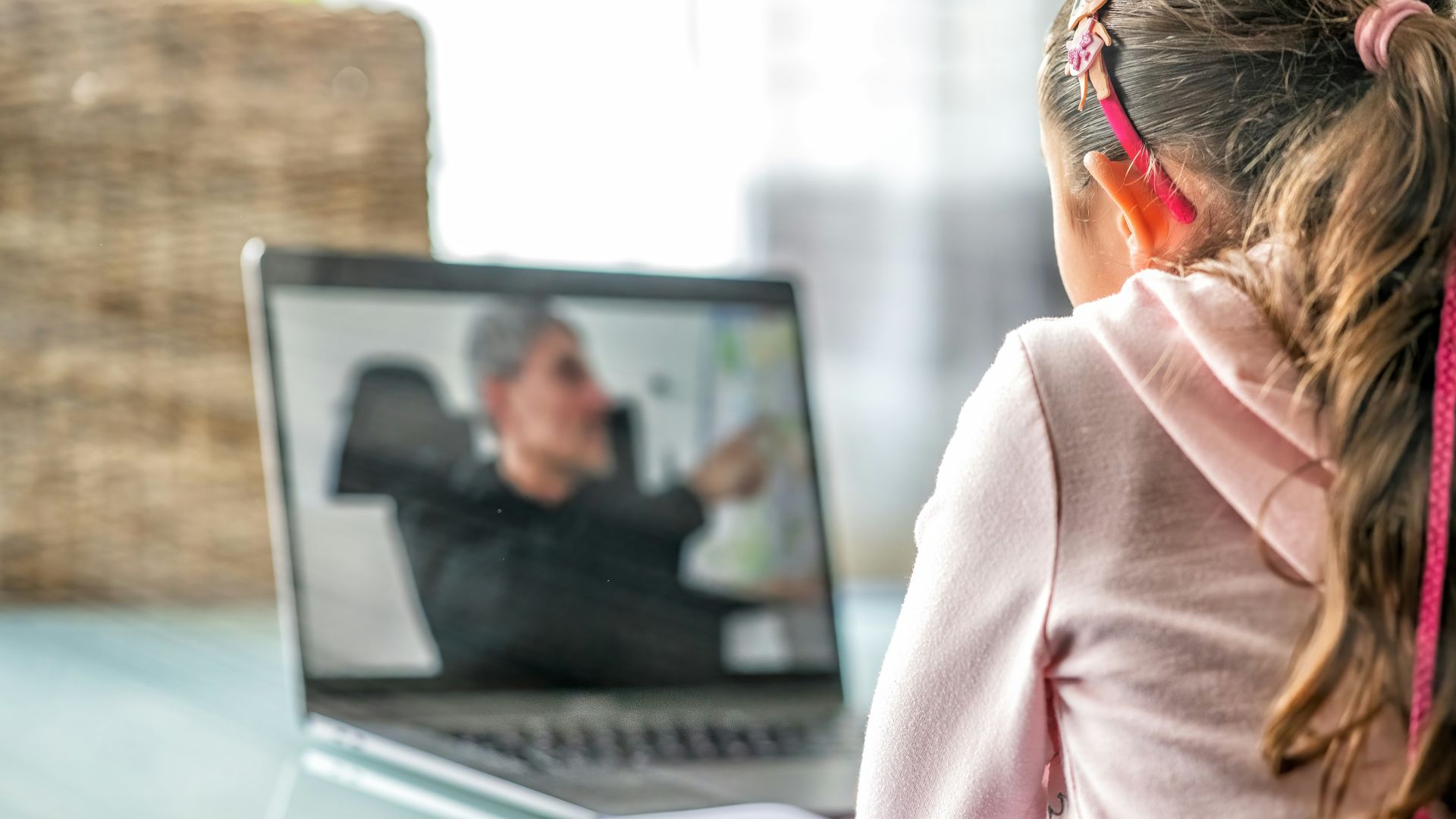 woman in pink long sleeve shirt sitting in front of macbook pro