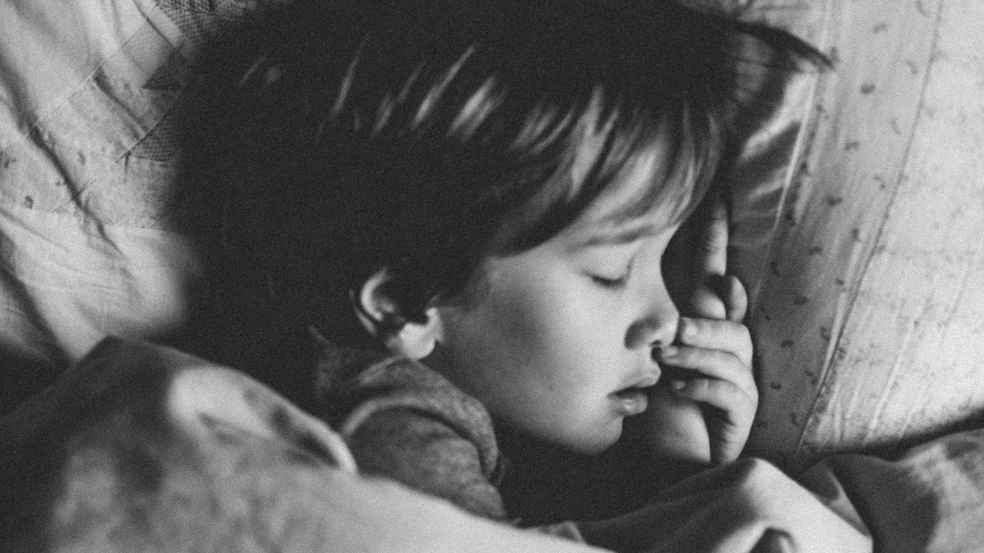 grayscale photo of girl sleeping on white pillow