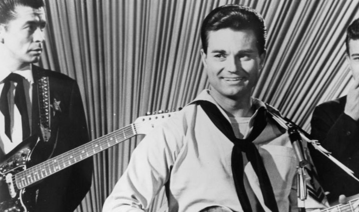 Leroy VanDyke plays a guitar in a scene of the movie 