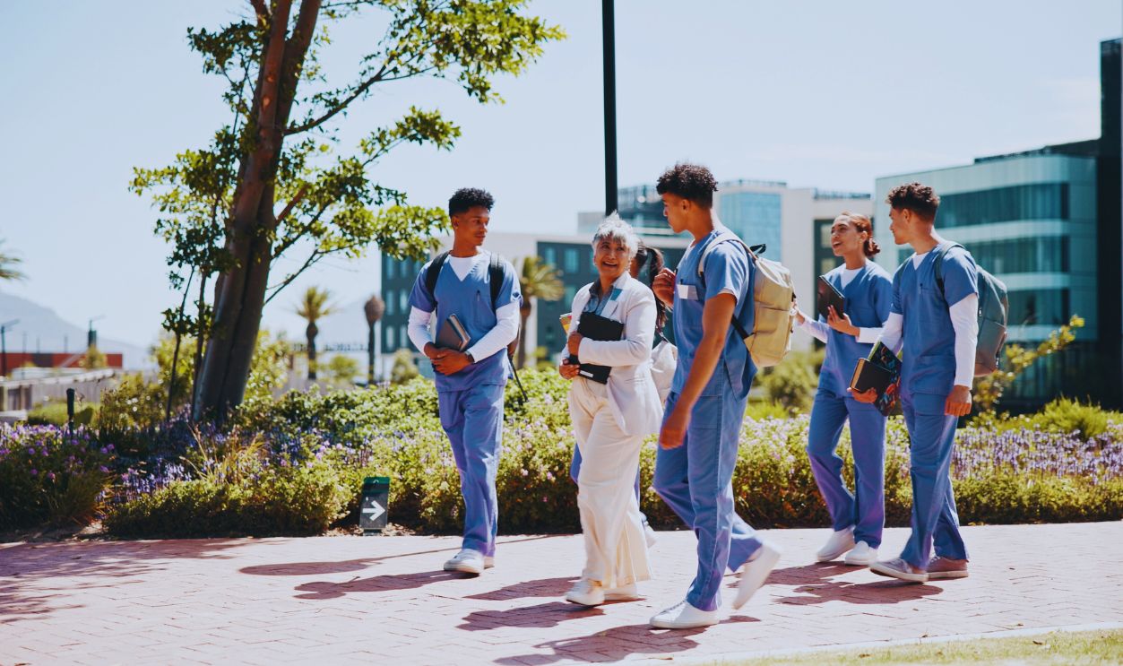 Medical student, university and professor with people in outdoor for college, healthcare and teacher. Scholarship, internship and doctors with students on hospital campus for assignment and education