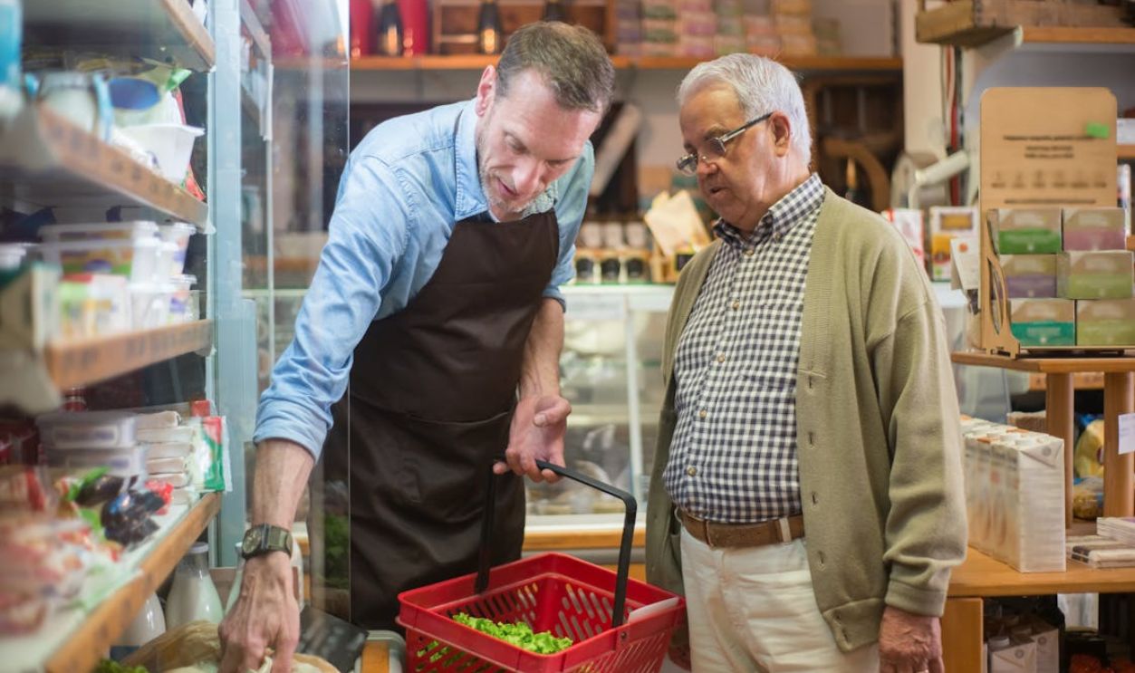 Man Wearing an Apron Helping a Elderly Man