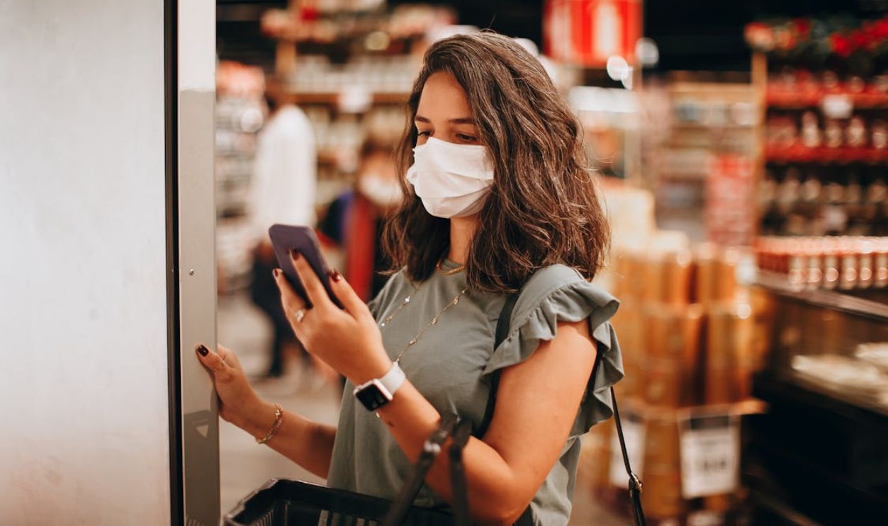 Woman in a Supermarket Looking at a Shopping List on her Smartphone