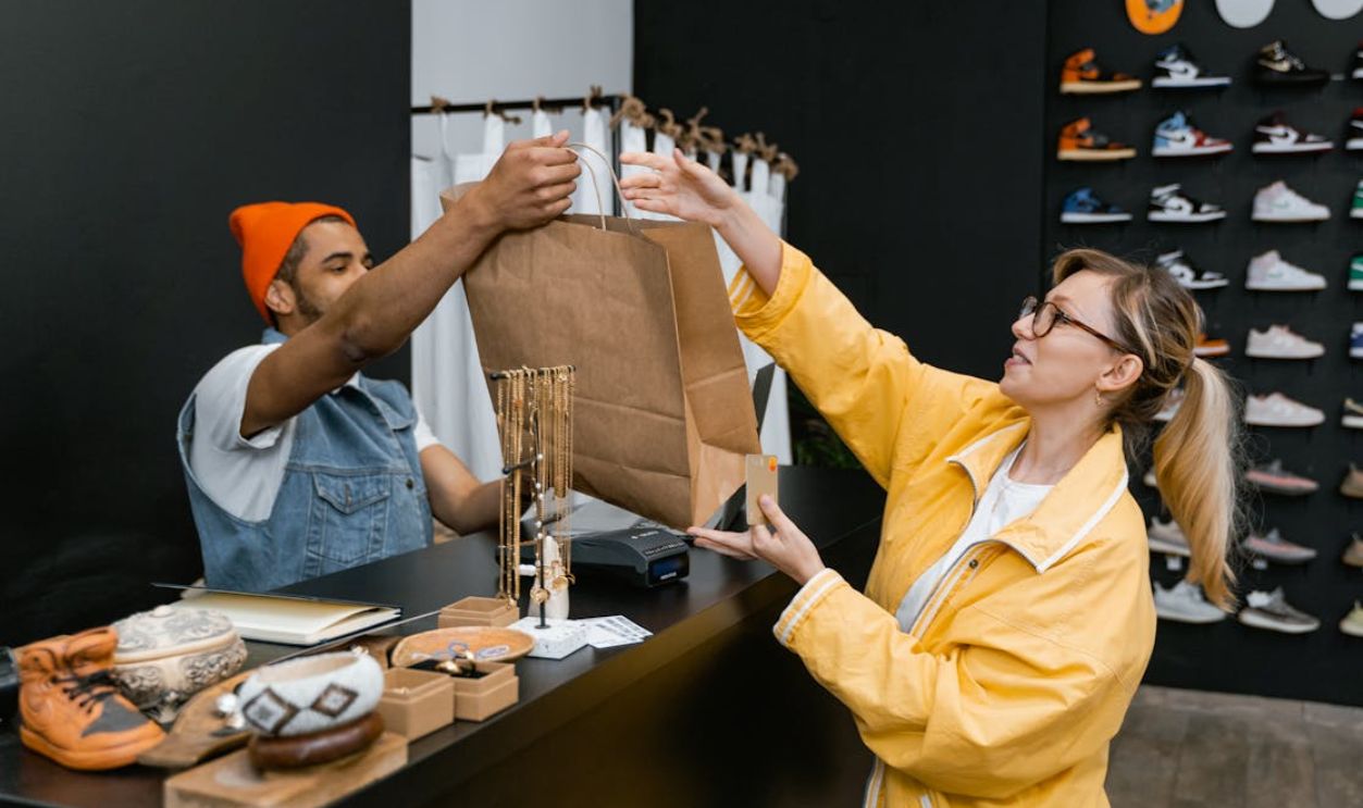 Man Handing Over a Shopping Bag to a Customer