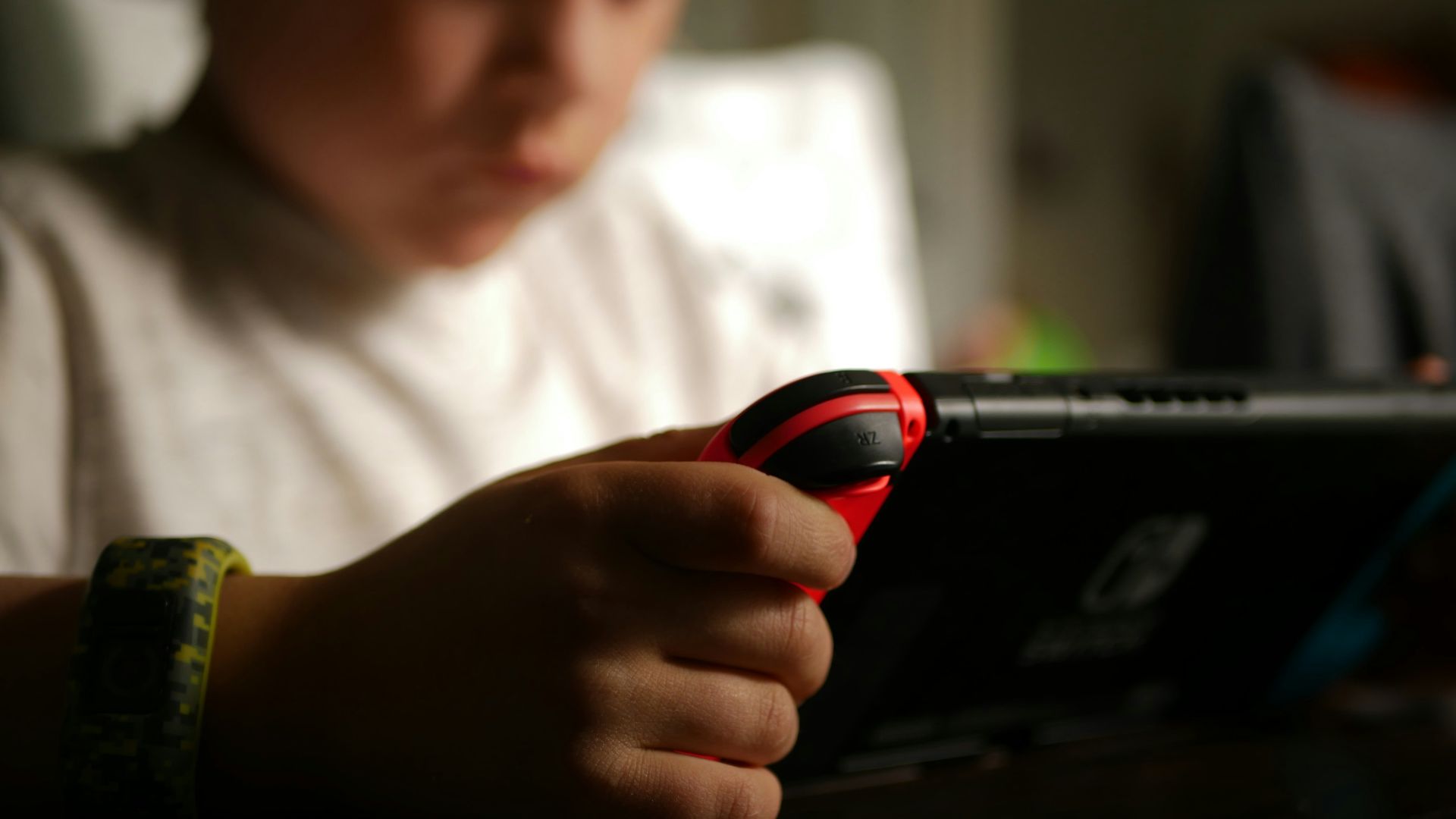 boy in white crew neck t-shirt holding black and red cordless device
