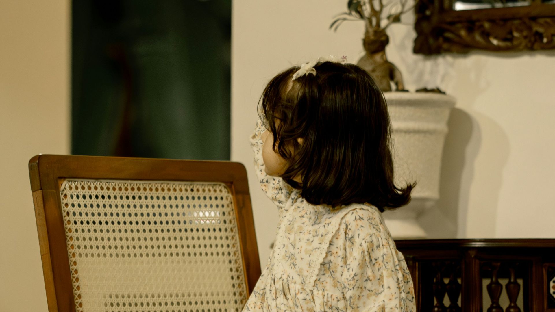 a little girl sitting on a wooden chair