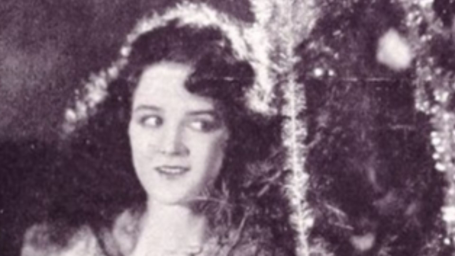 Actress Mary Philbin hiding behind a Christmas tree, on page 69 of the December 27, 1924 Exhibitors Herald.