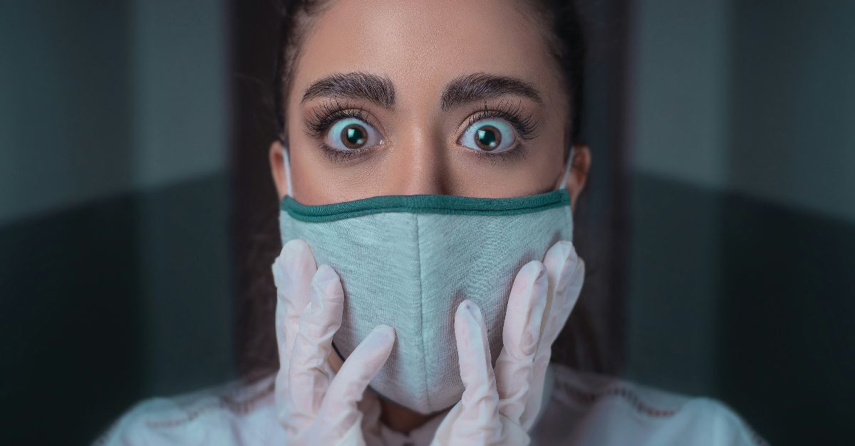 woman in white long sleeve shirt covering her face with blue and black face mask