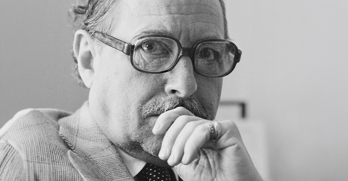 Black and white portrait of Tennessee Williams in his older years, wearing glasses.