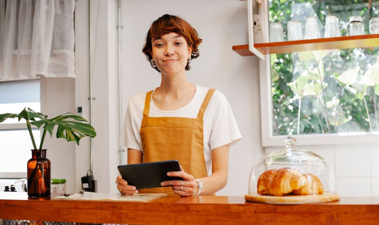 Smiling employee with tablet at counter in bakery