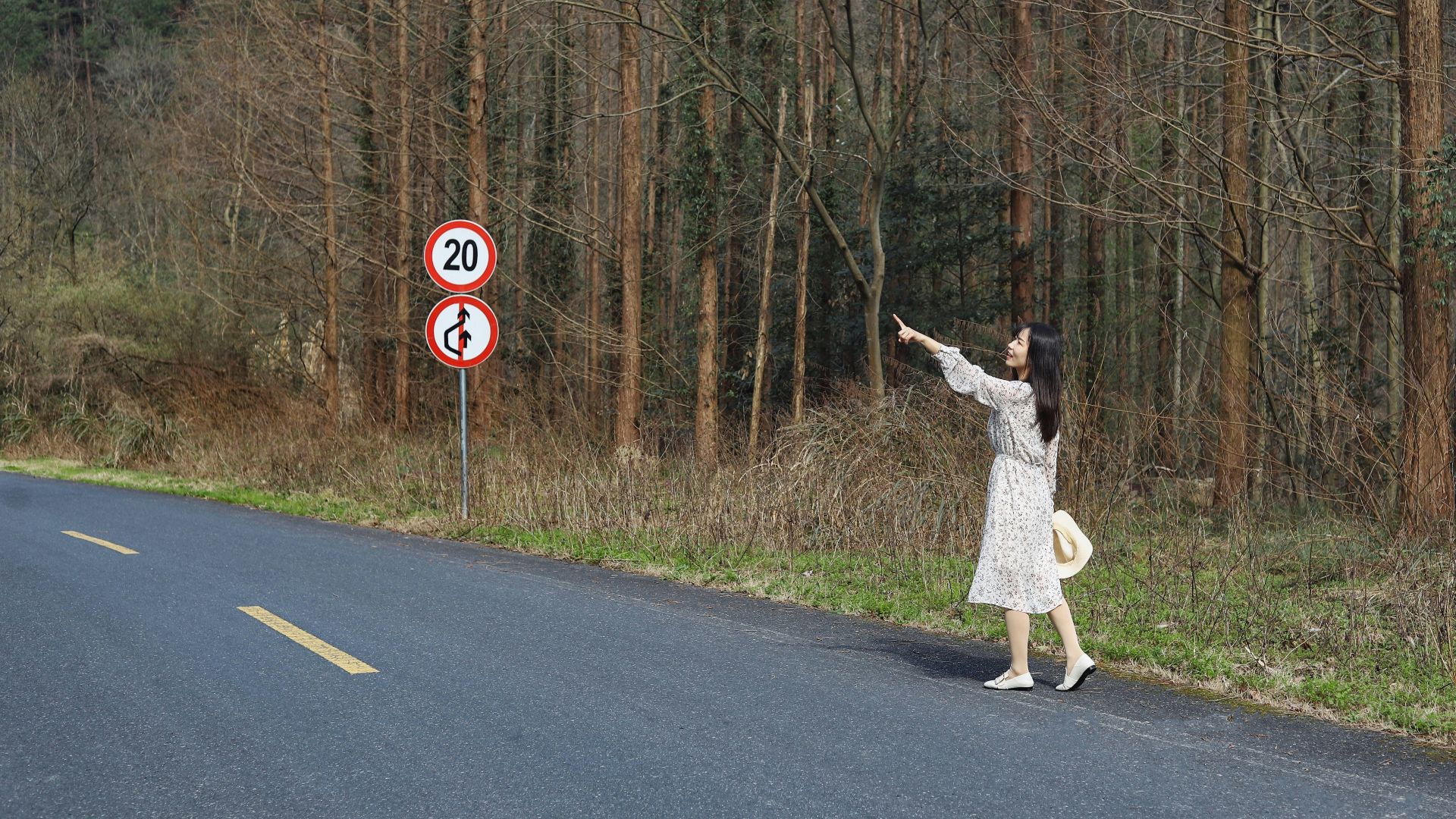 woman near 20 road signage surrounded by trees