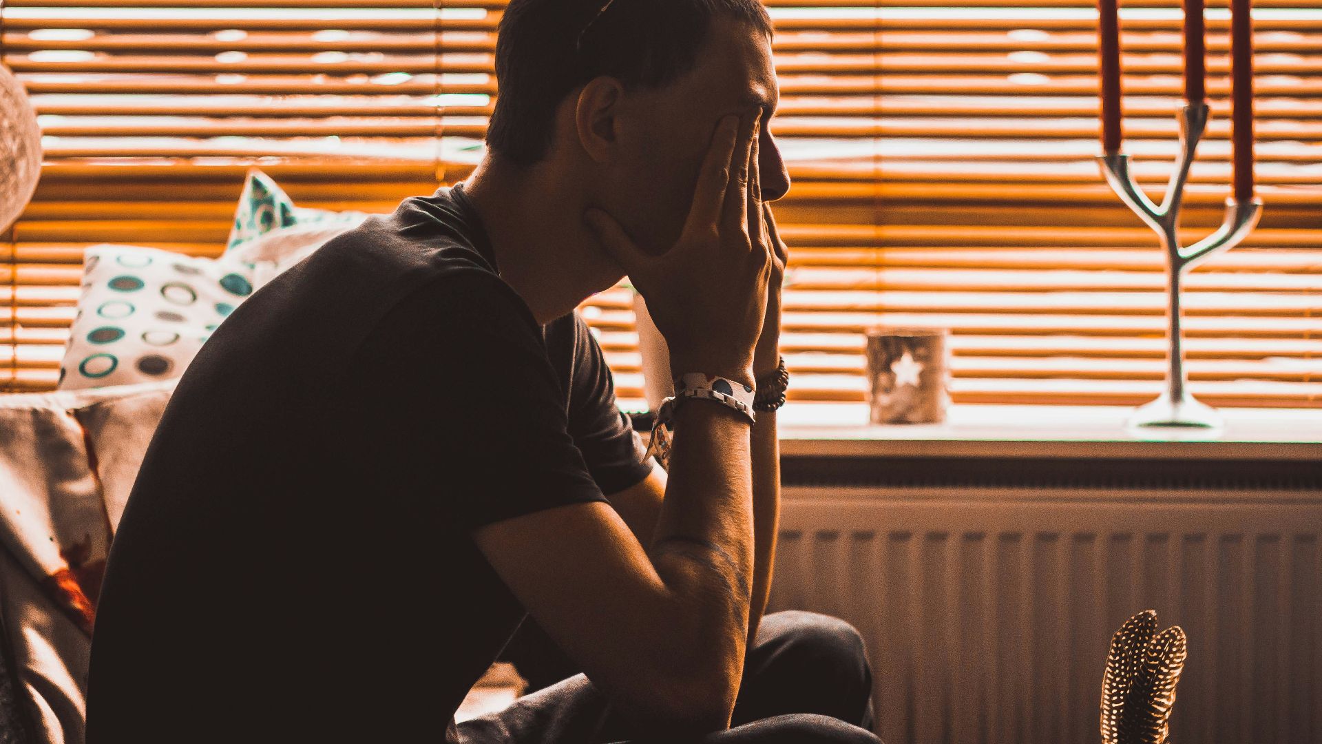 man sitting on chair covering his eyes