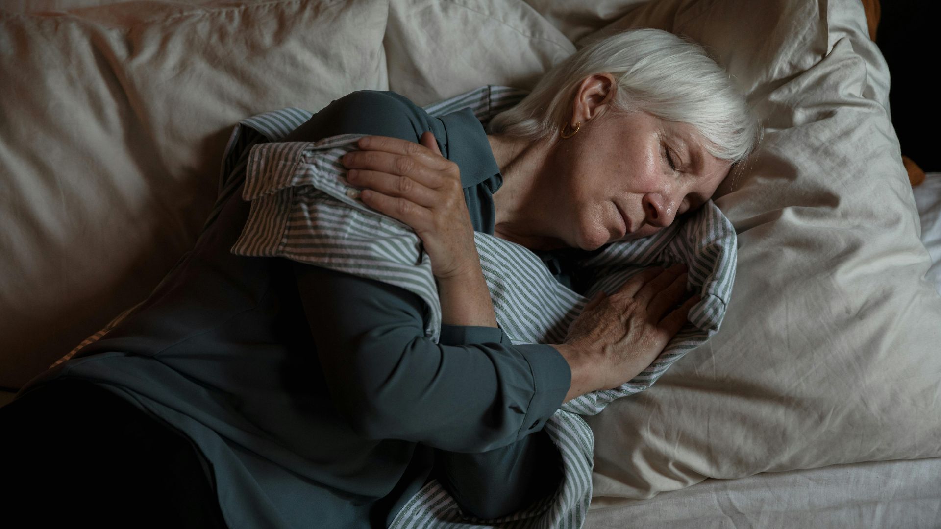 Senior woman sleeping peacefully in bed, conveying tranquility and rest.