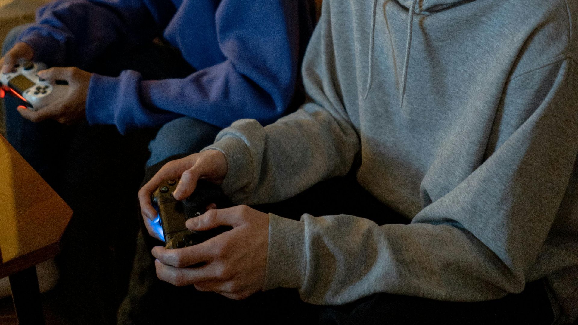 Two teenagers play video games together indoors, focused and relaxed.