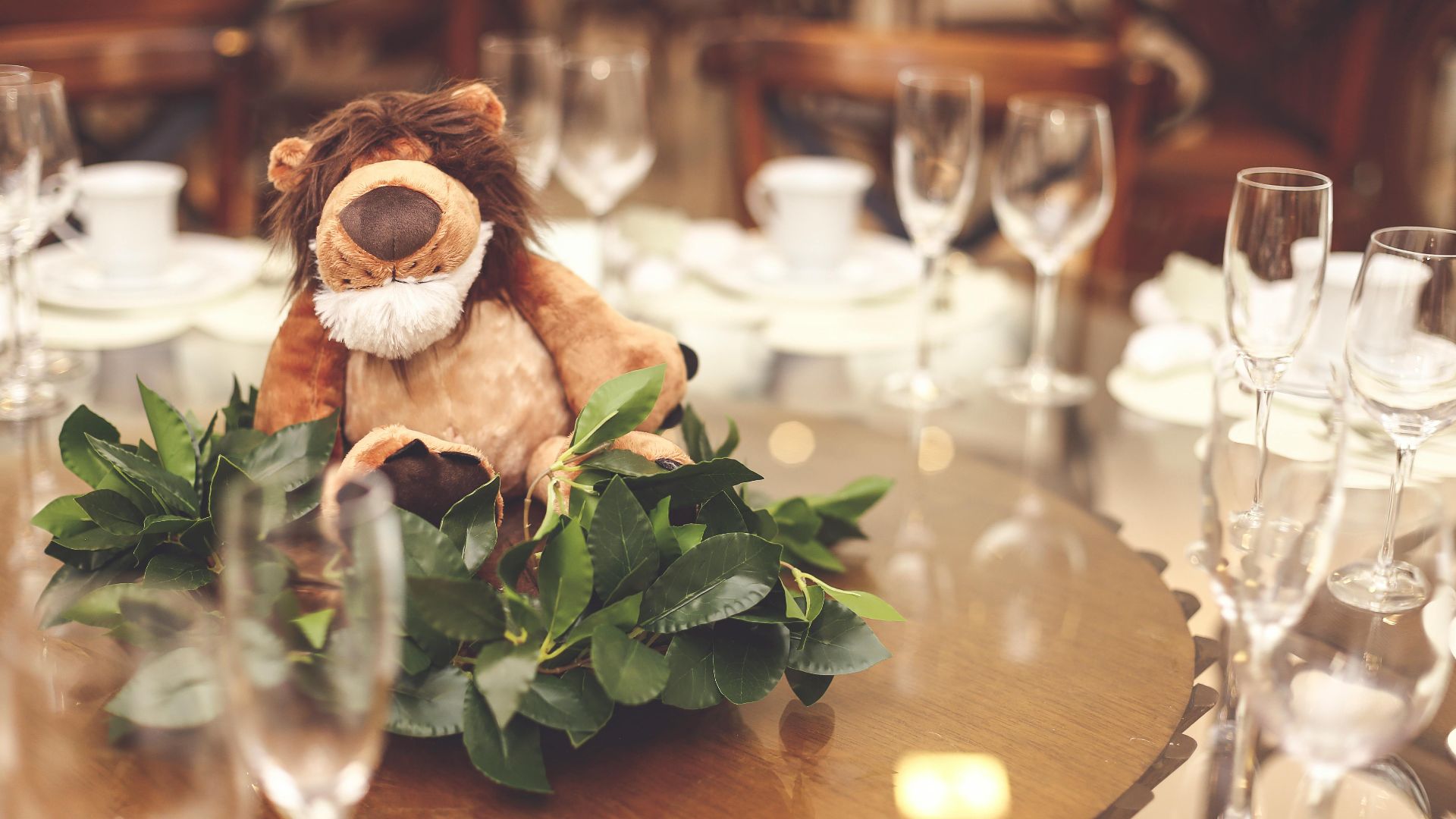 Sophisticated dining table with plush lion centerpiece and elegant glassware.