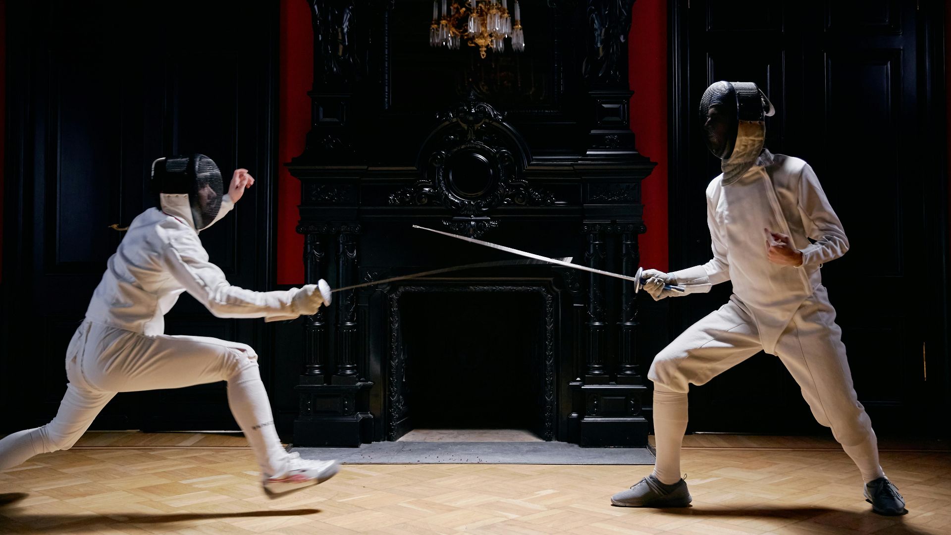 Two adults in full fencing gear engage in a dynamic duel in an ornate indoor environment.