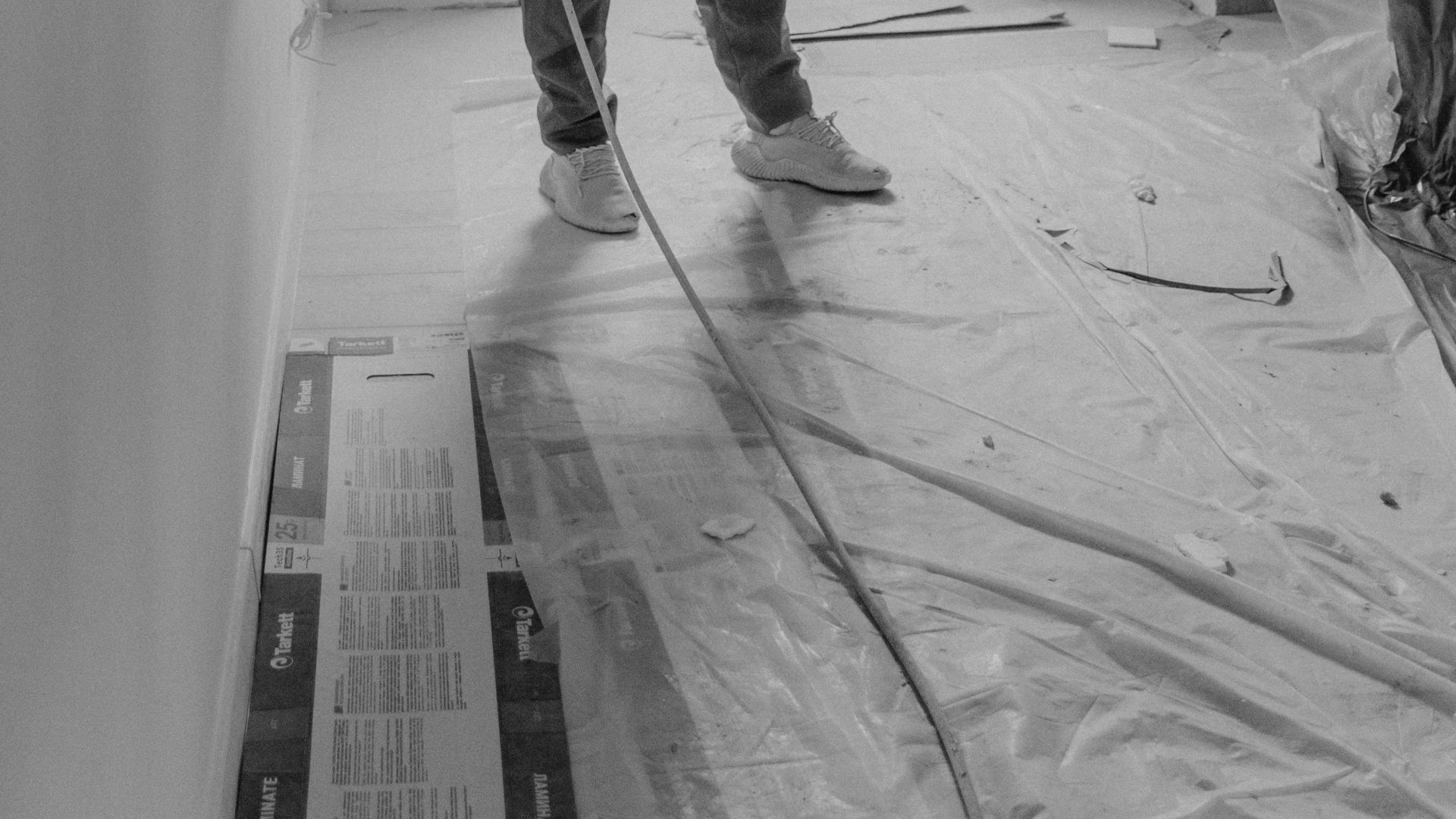 Black and white image of a person painting a room, focusing on renovation and improvement.